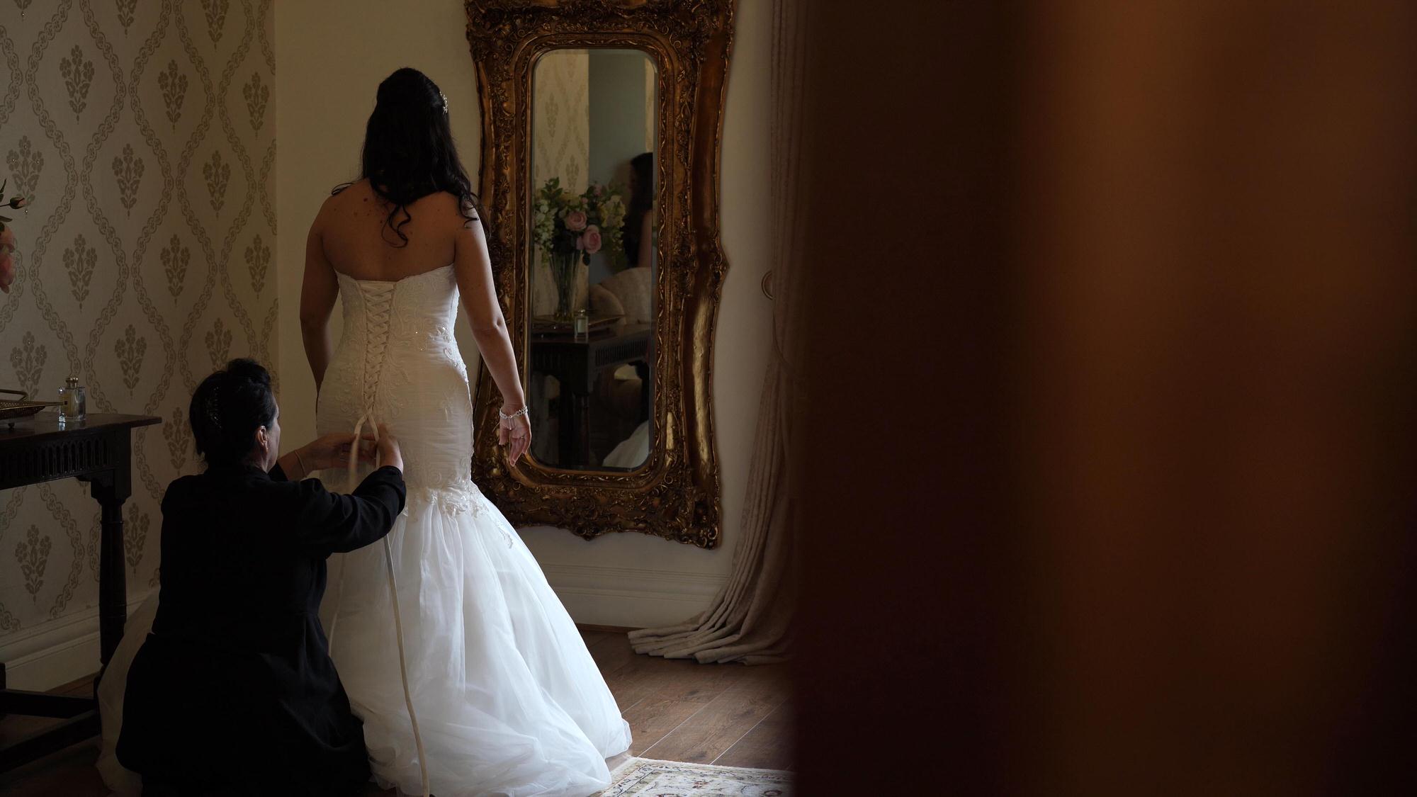 the bride is helped in to her wedding dress in the bridal suite