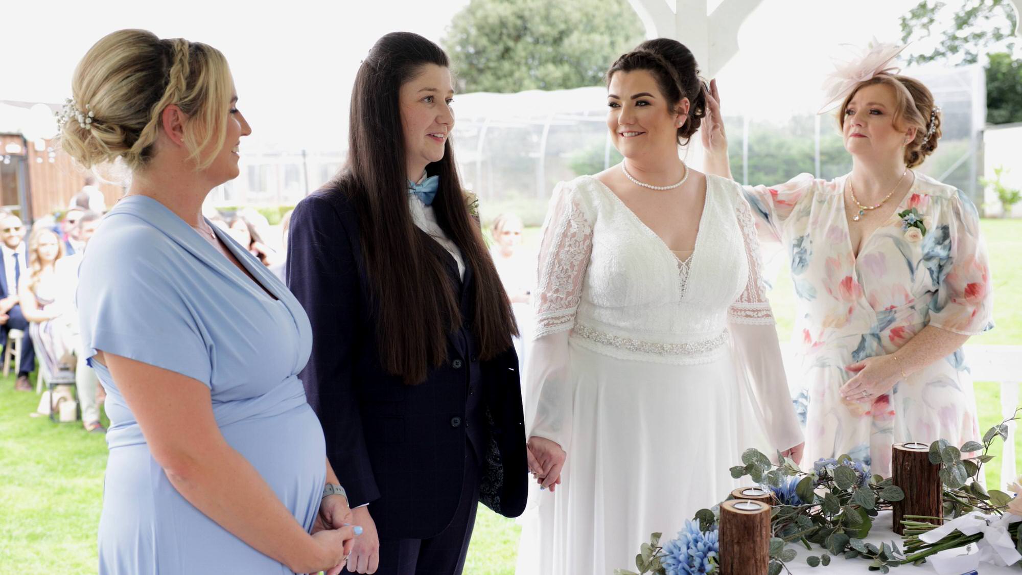 a brides mum fixes her daughters hair during the ceremony
