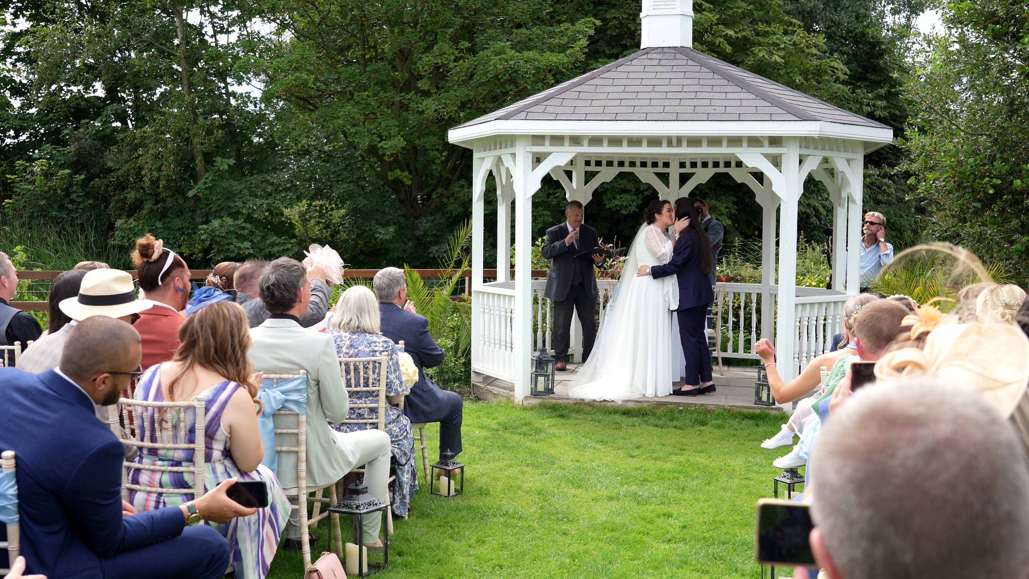 the brides kiss during their outdoor wedding ceremony at The Aviary in Ormskirk