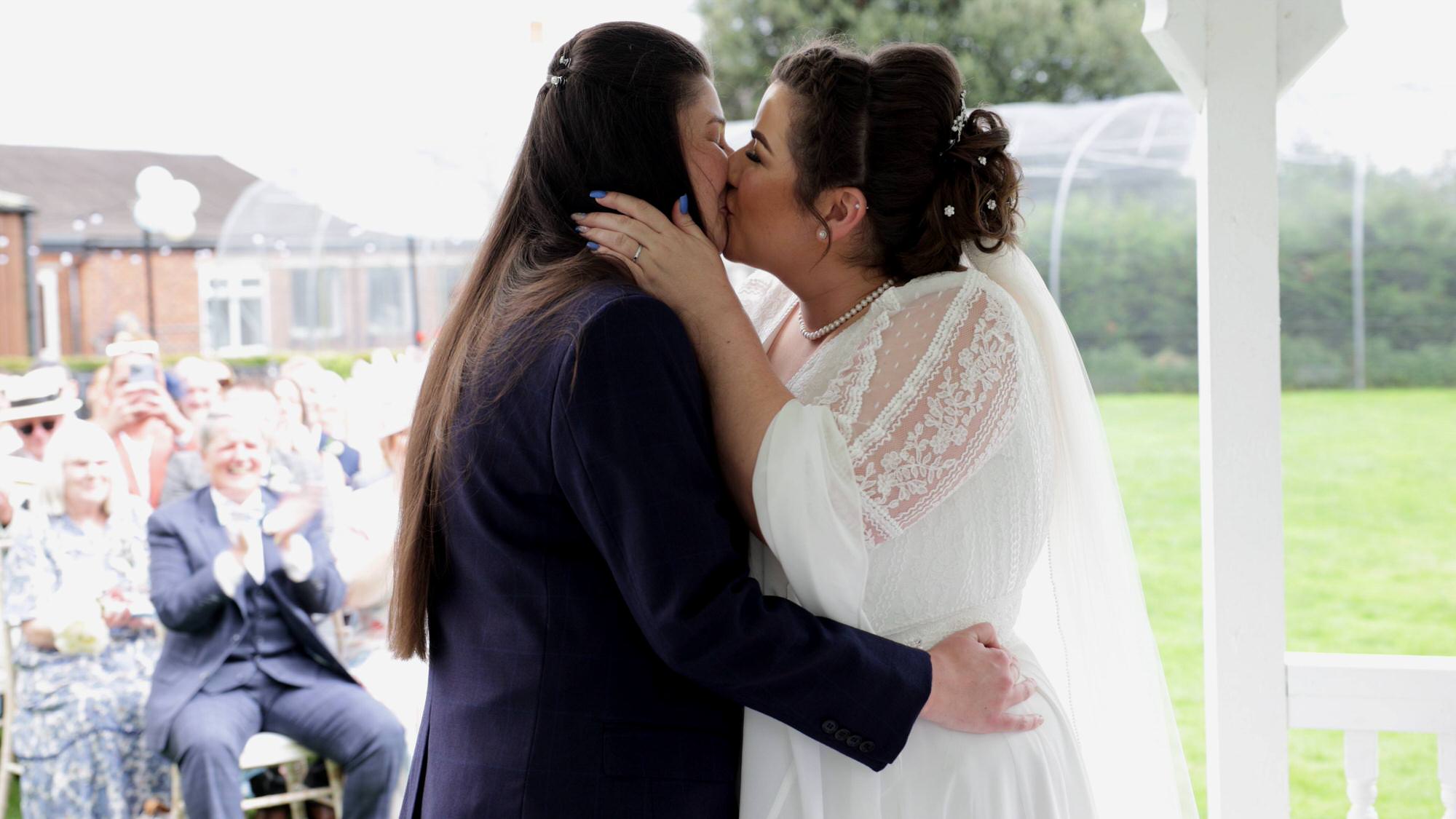 a close up video still of two brides kissing during their wedding ceremony at The Aviary in Lancashire