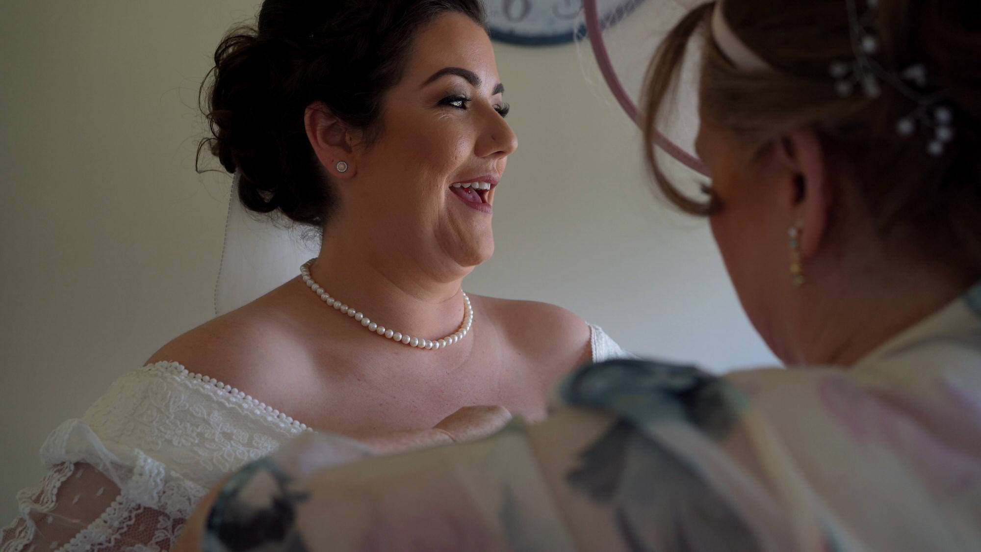 a Mum helps her daughter get dressed on her wedding morning