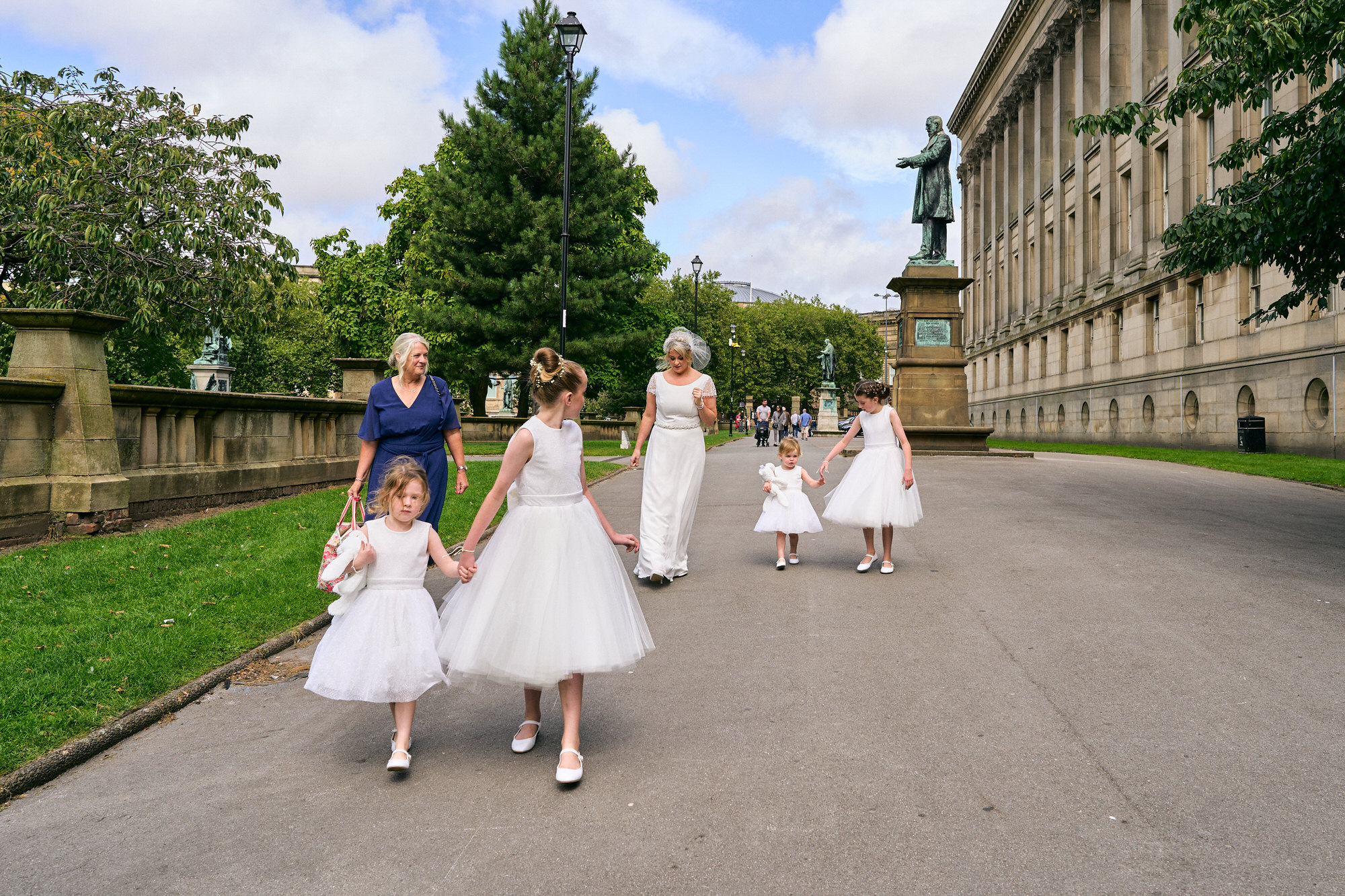 the bride walks behind St Georges Hall with her bridal party