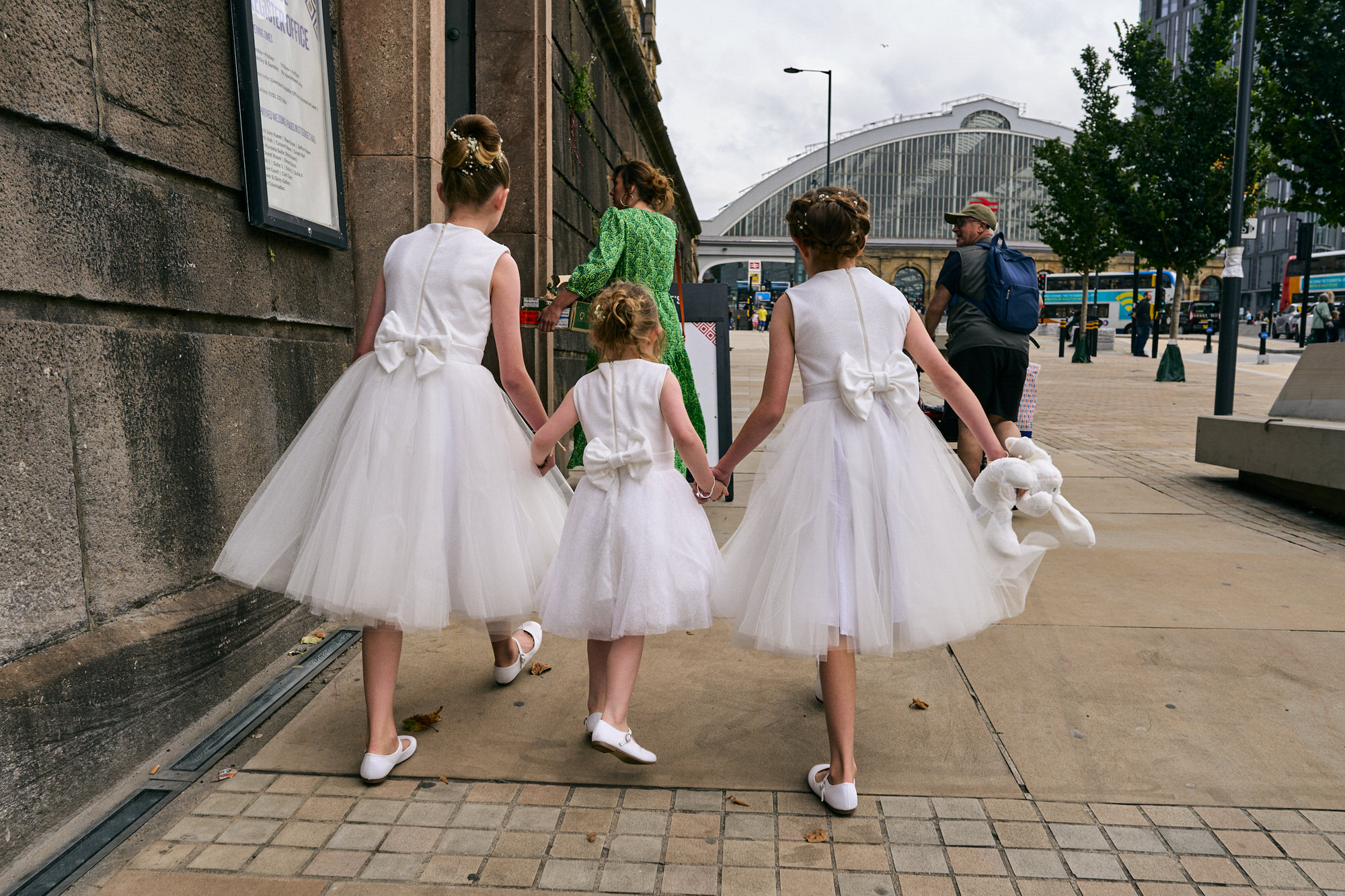 flower girls hold hands and walk towards st georges hall