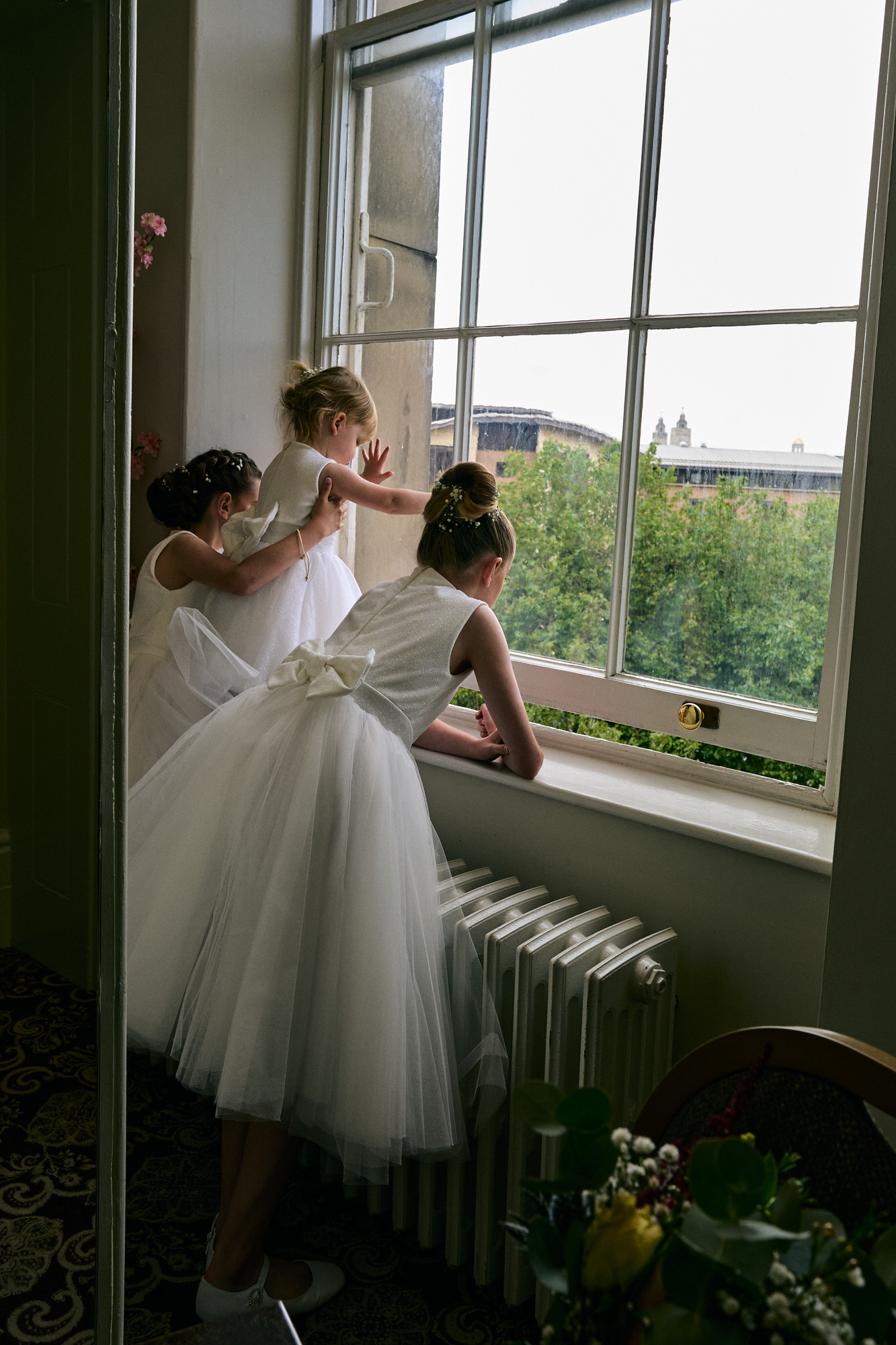a natural photo of flower girls looking out of a window at St Georges Hall