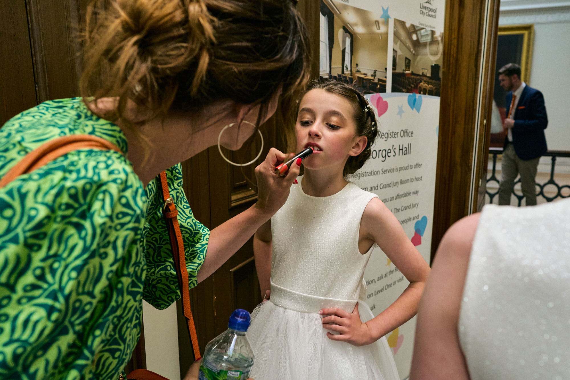 A flower girl gets her lip gloss done before the wedding ceremony