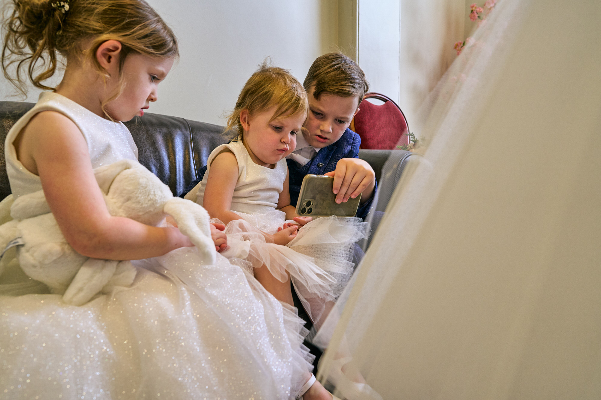 flower girls and a pageboy watch a video before the ceremony