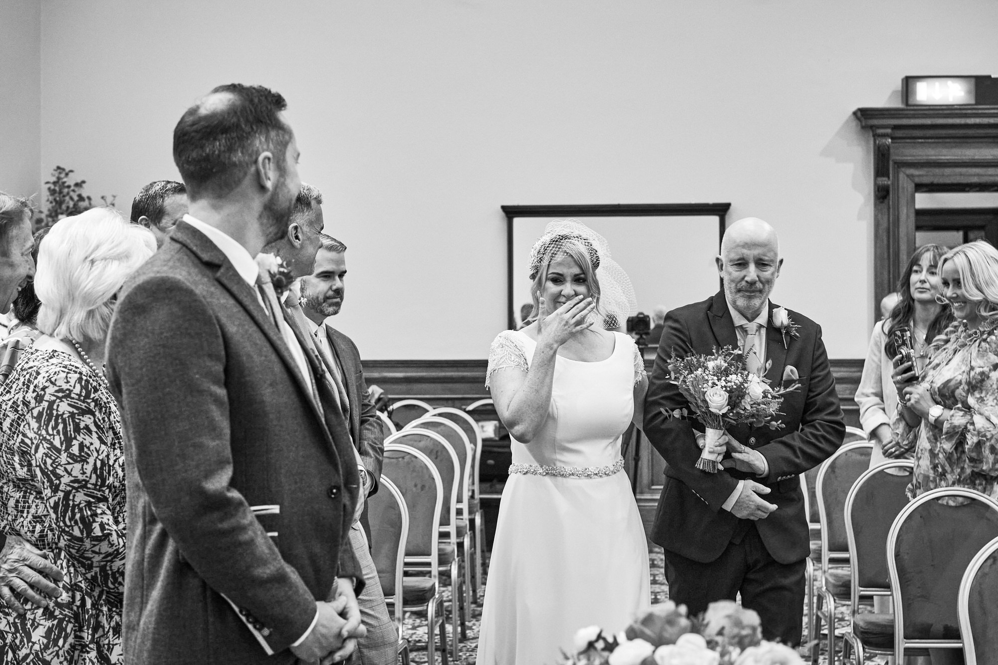 a natural photo of a Bride holding back tears as she walks down the aisle at St Georges Hall
