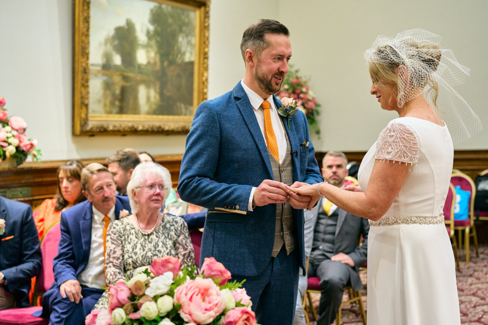 the groom places the wedding ring on the bride