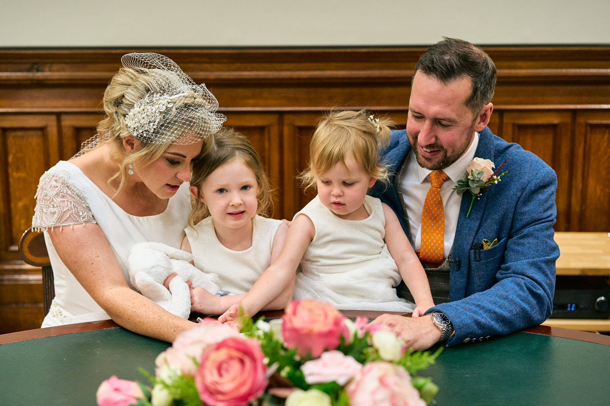 the family sit to sign the wedding register at St Georges Hall