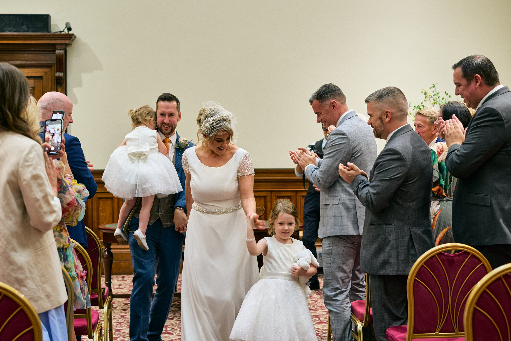 the couple walk back down the aisle with their two daughters at St Georges Hall