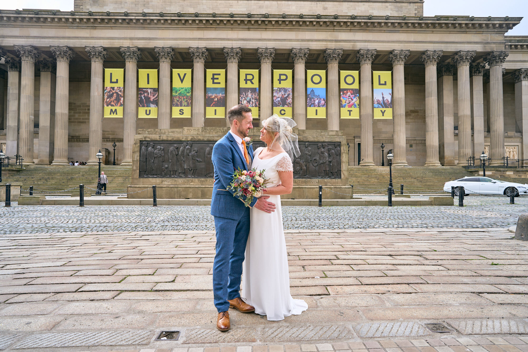 a wide shot of a couple outside St Georges Hall with a large Liverpool banner