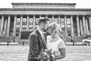 a couple kiss outside the historic St Georges Hall in Liverpool