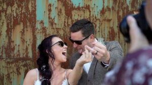 a couple have fun with the wedding videographer and photographer outside the barn at morleys hall