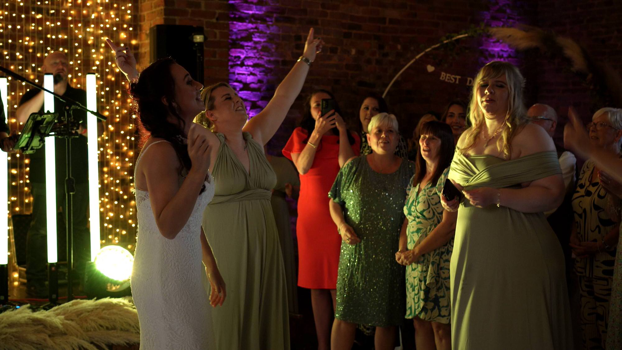 bride is joined by her bridesmaids for a sing off at her wedding party
