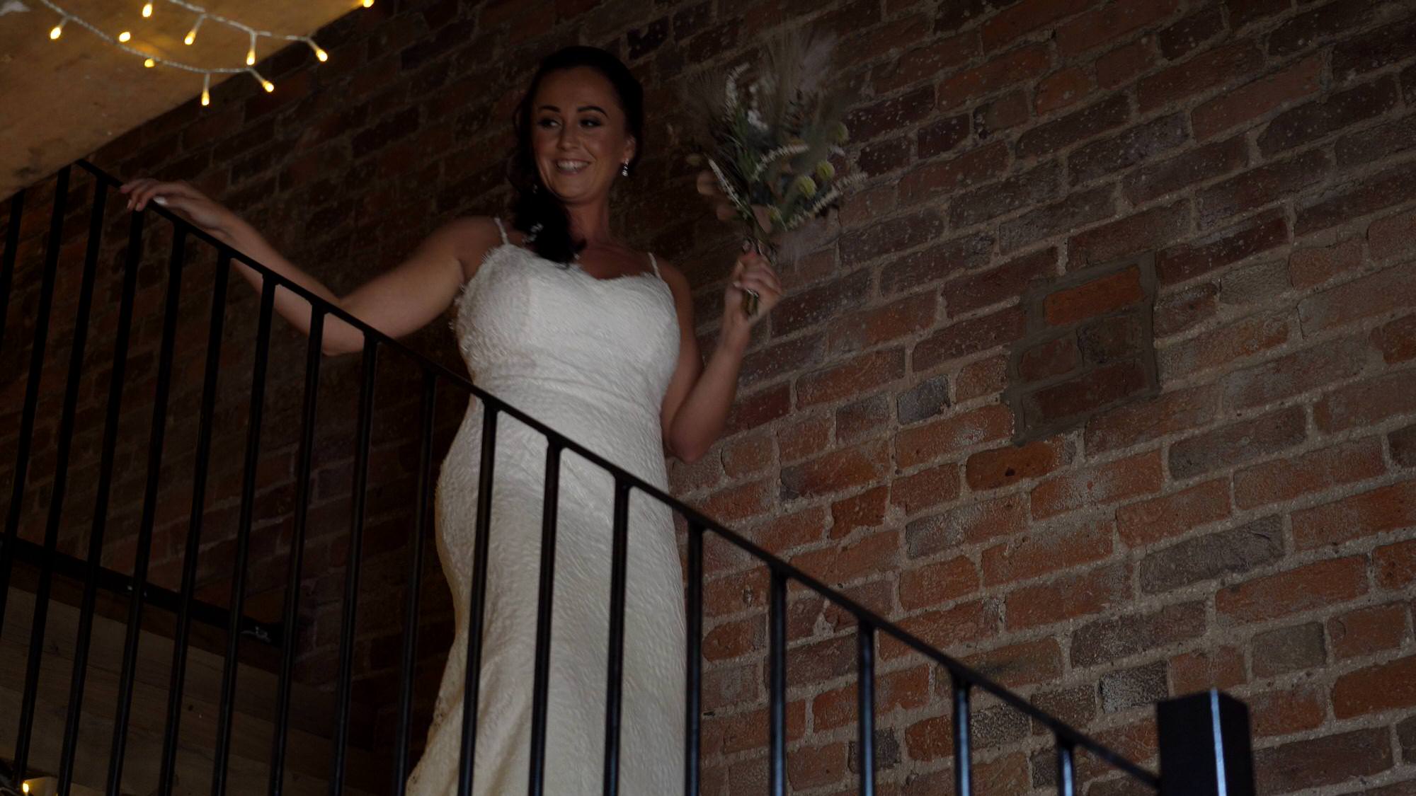 a bride walks down the stairs for a first look at the barn at morleys hall