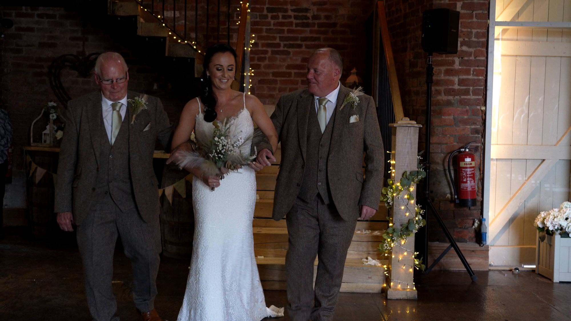 a bride walks down the aisle with her dad and grandad