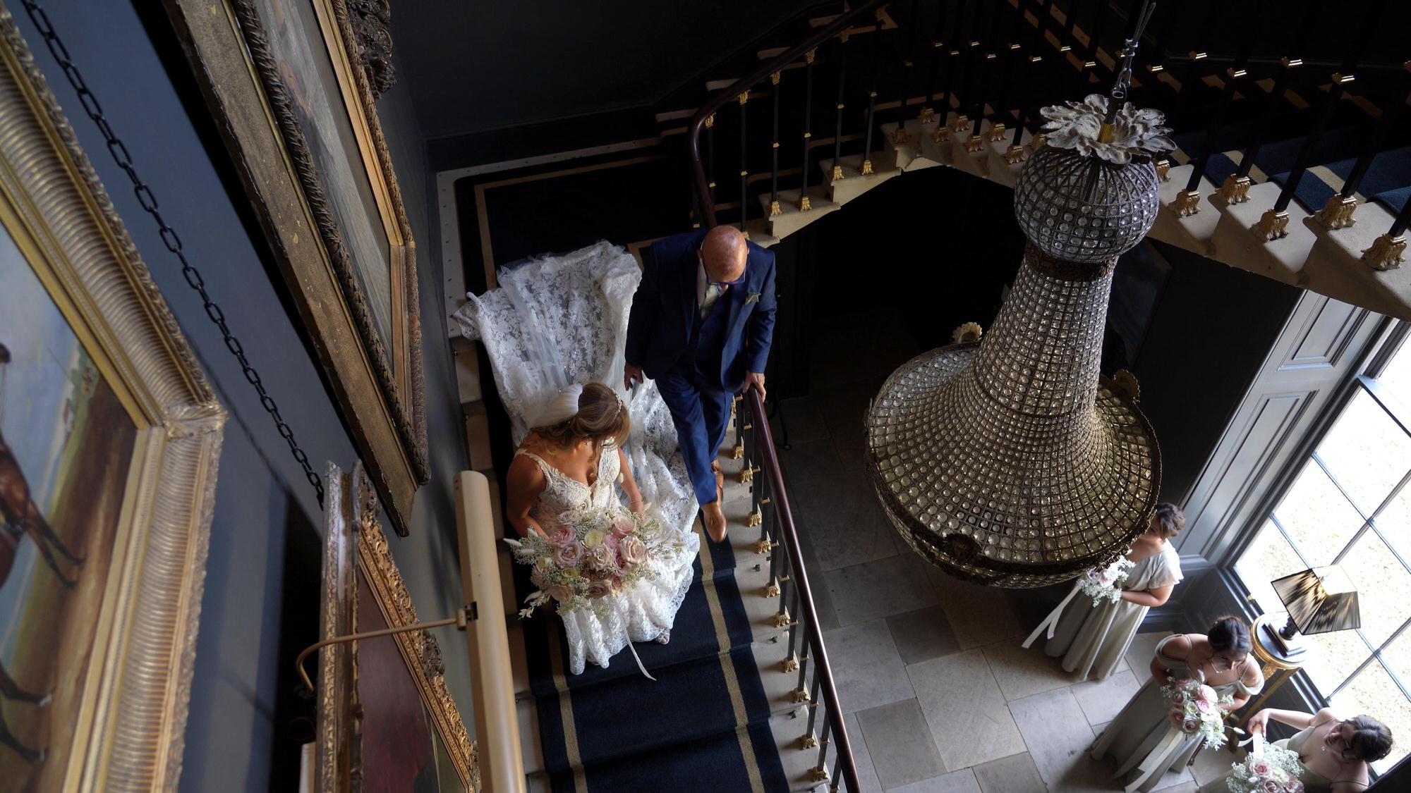 a bride and her grandad walk down the grand staircase at Stubton Hall Newark