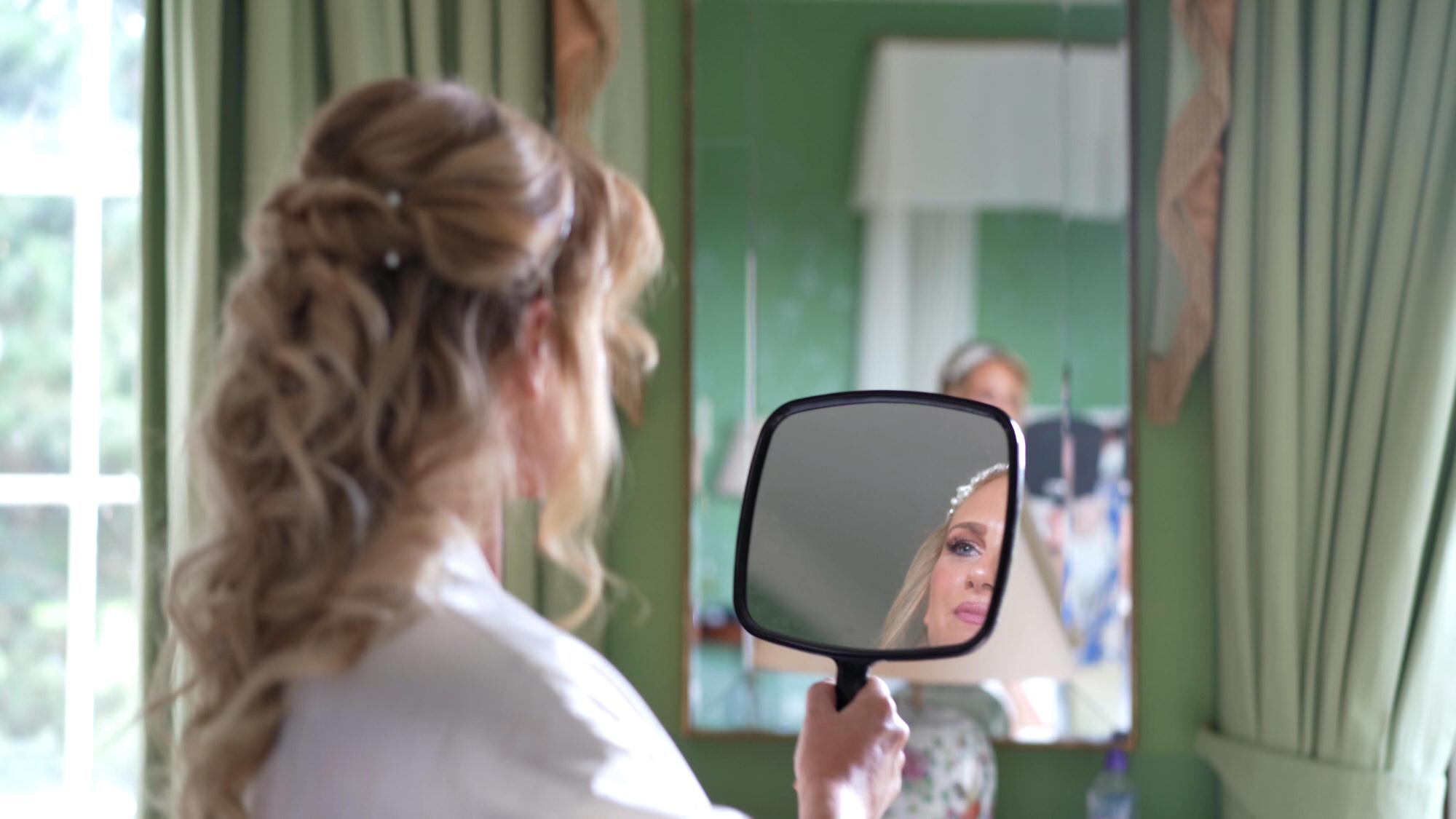 a bride checks her hair in the mirror at Stubton Hall Newark