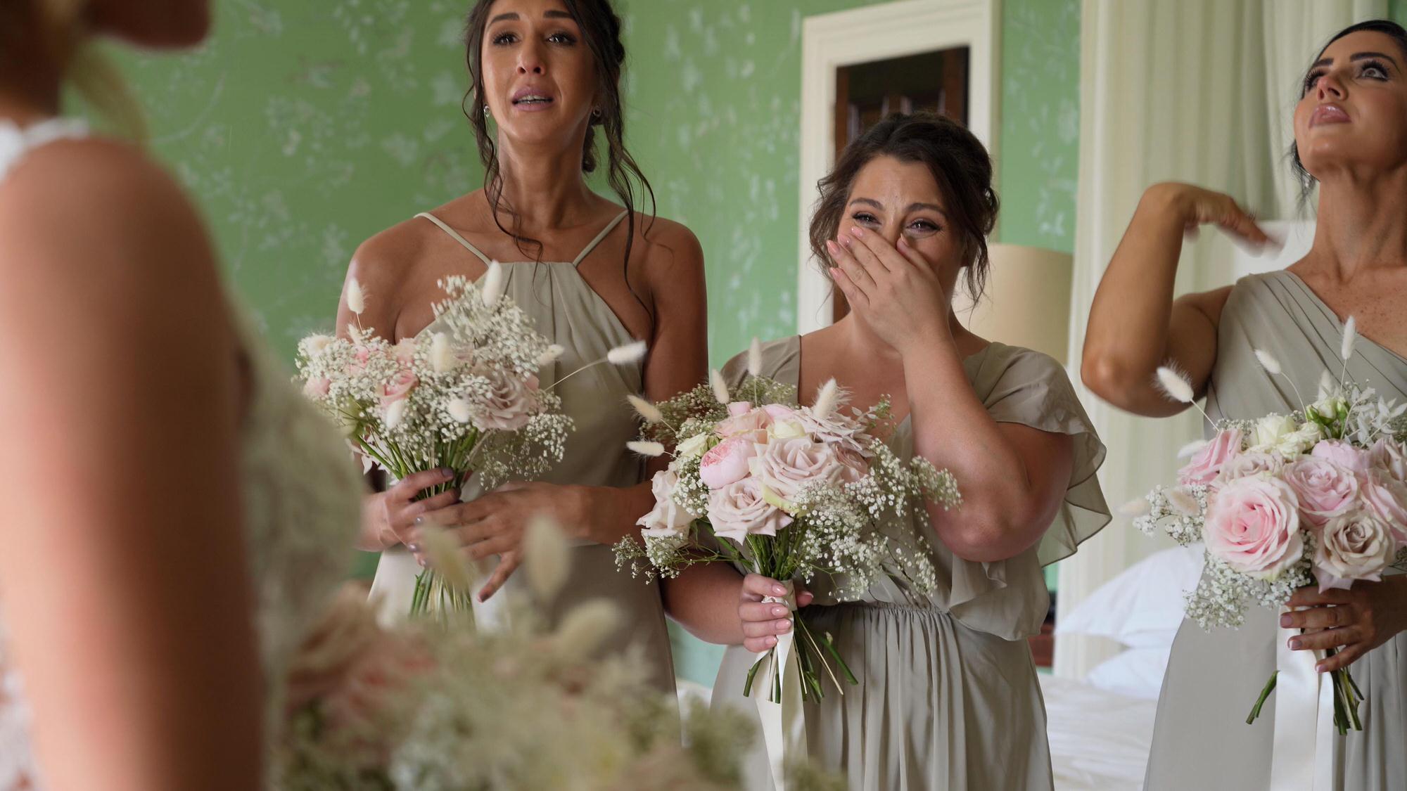 a bridesmaid covers her face to hold back tears