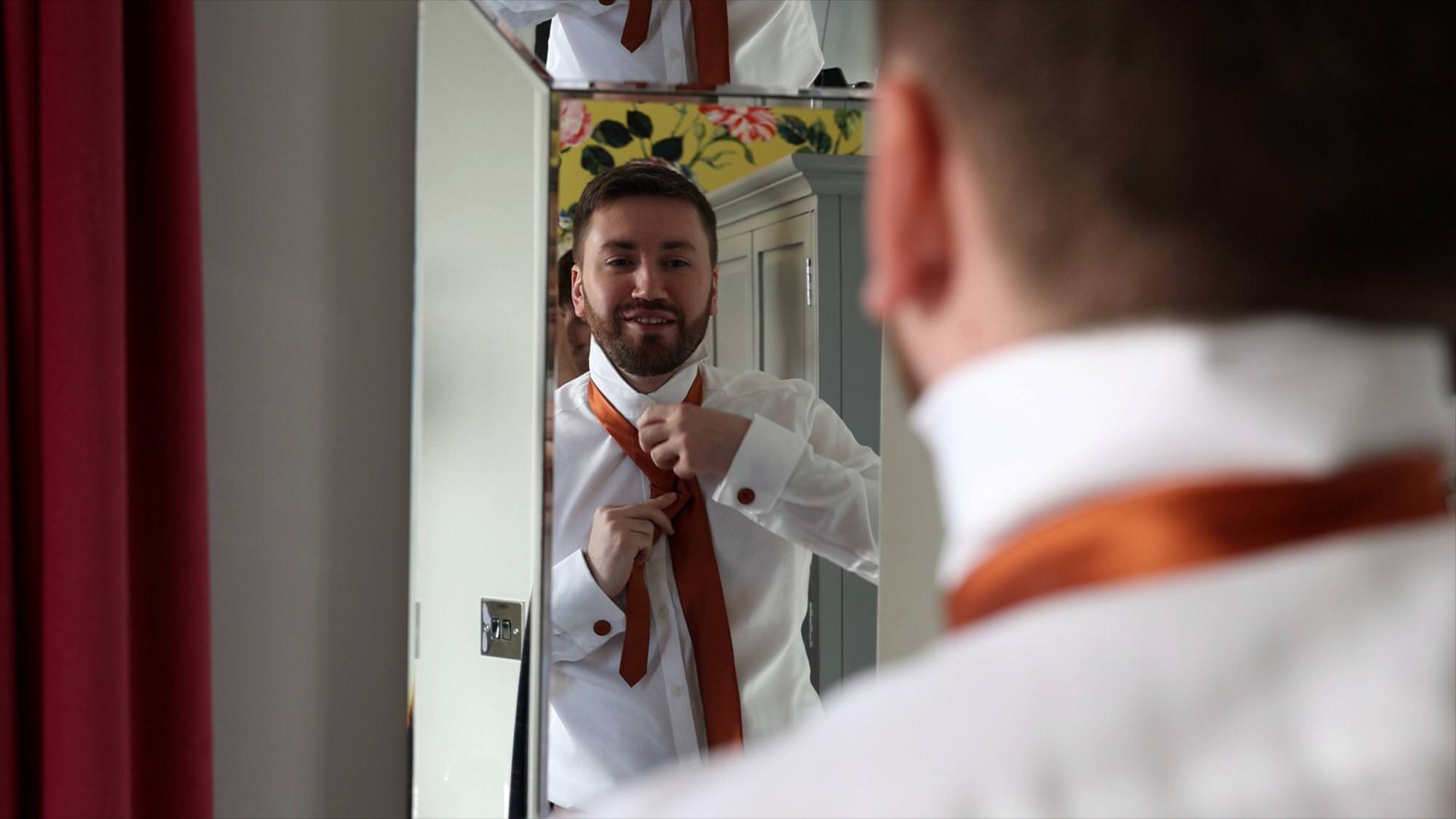groom getting ready in a mirror at Cartmel Old Grammar