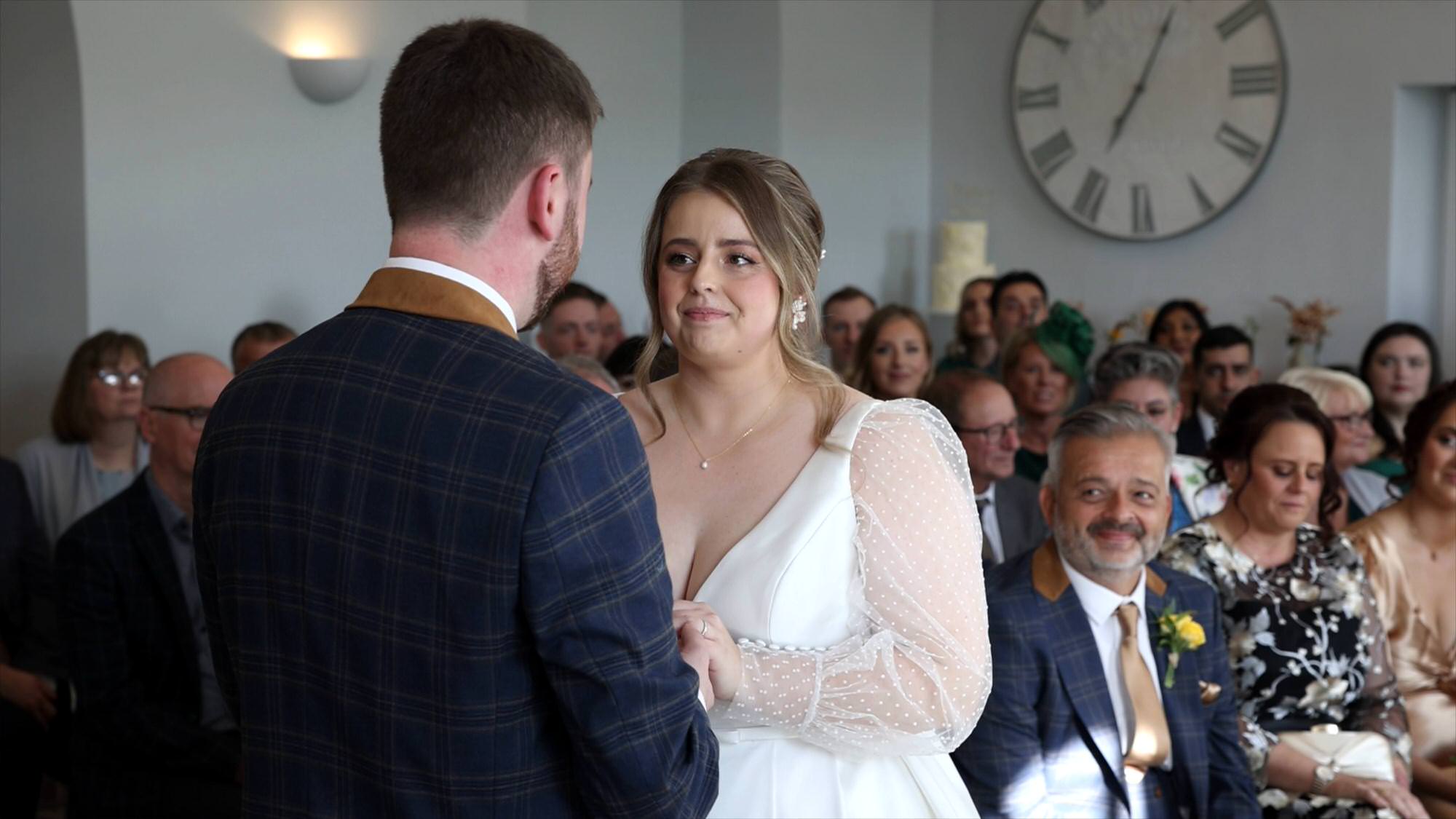 a bride looks up at her groom as they exchange wedding rings