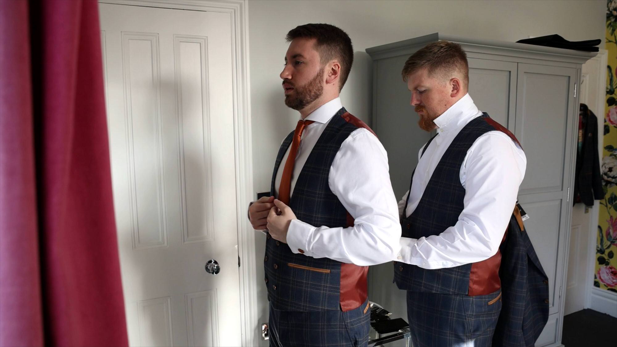 groom gets help with his wedding waistcoat before his lake district wedding