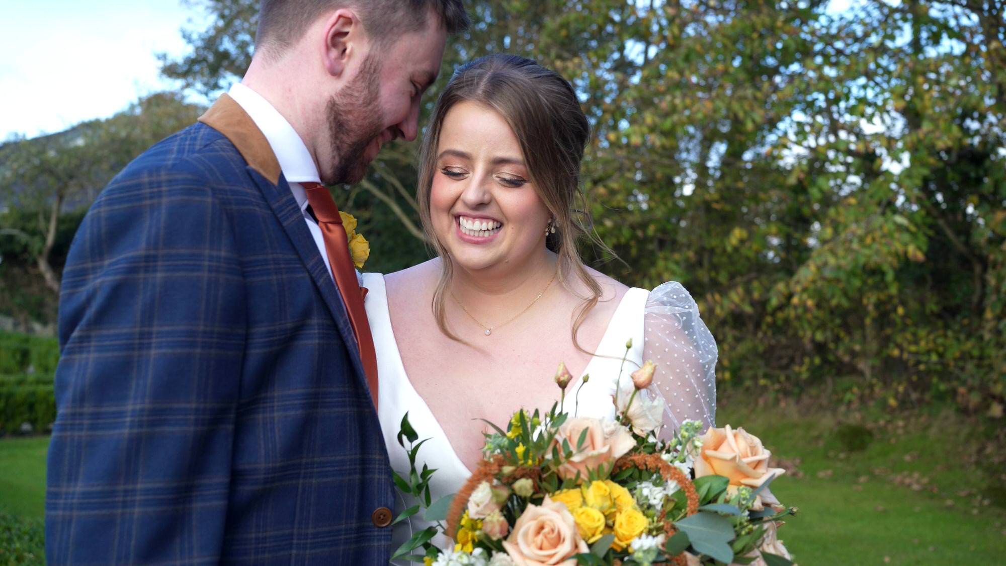 a videographer captures a natural giggle with the couple during their wedding photos