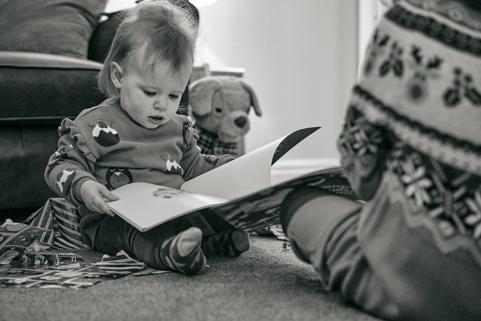 a black and white photo of a little girl reading her christmas even book