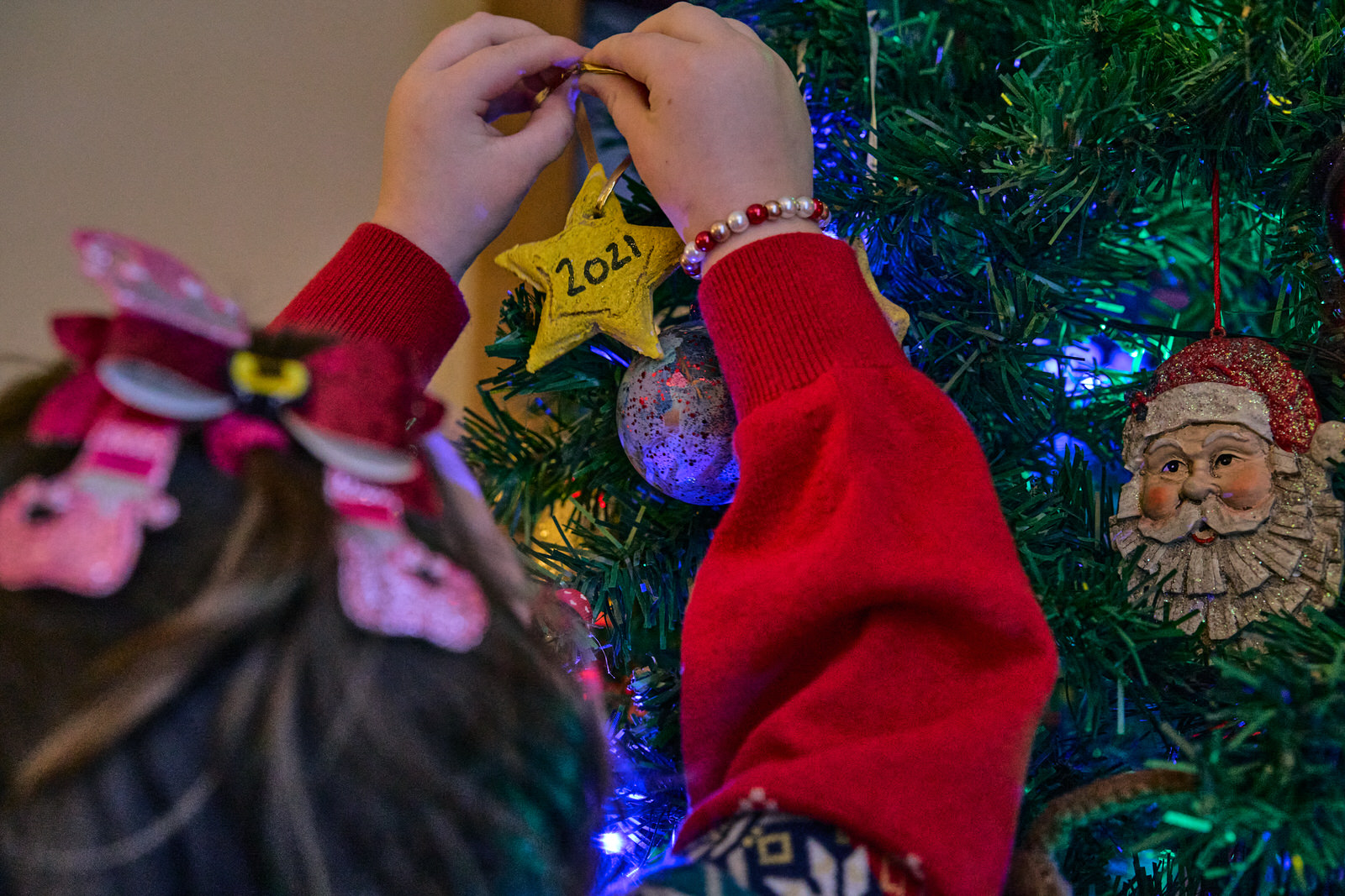 a girl hangs a handmade christmas decoration to the tree