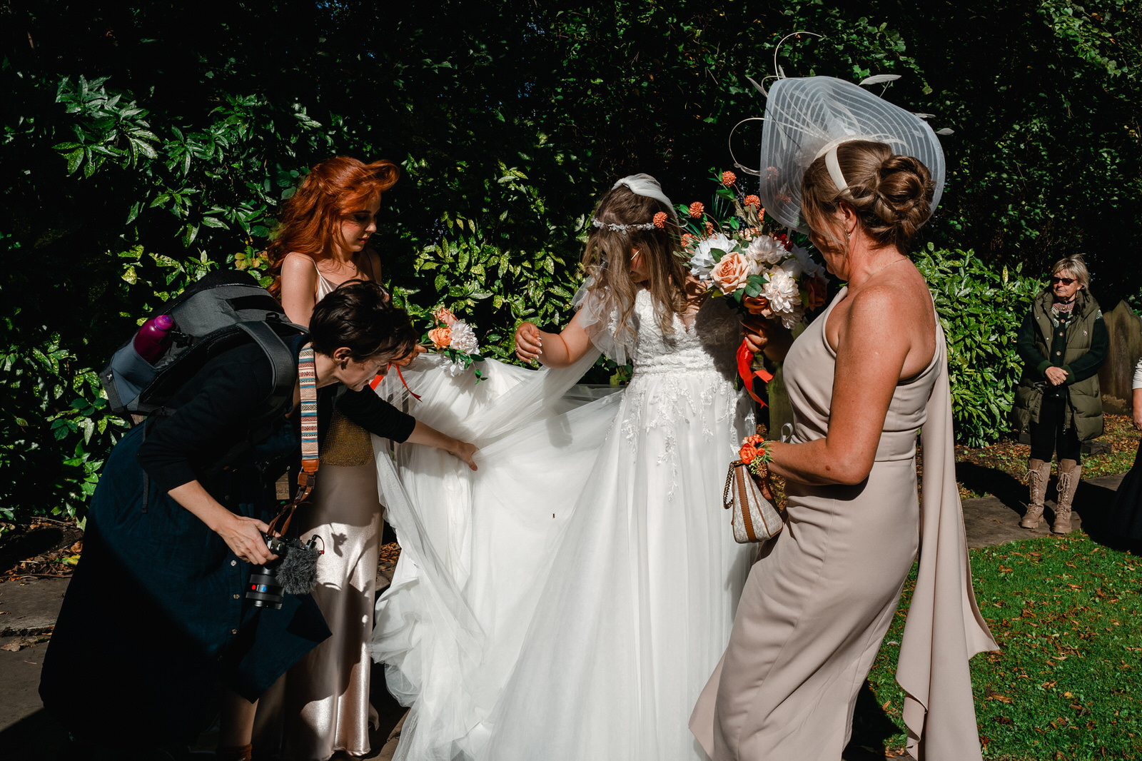 a wedding videographer helps a bride with her dress