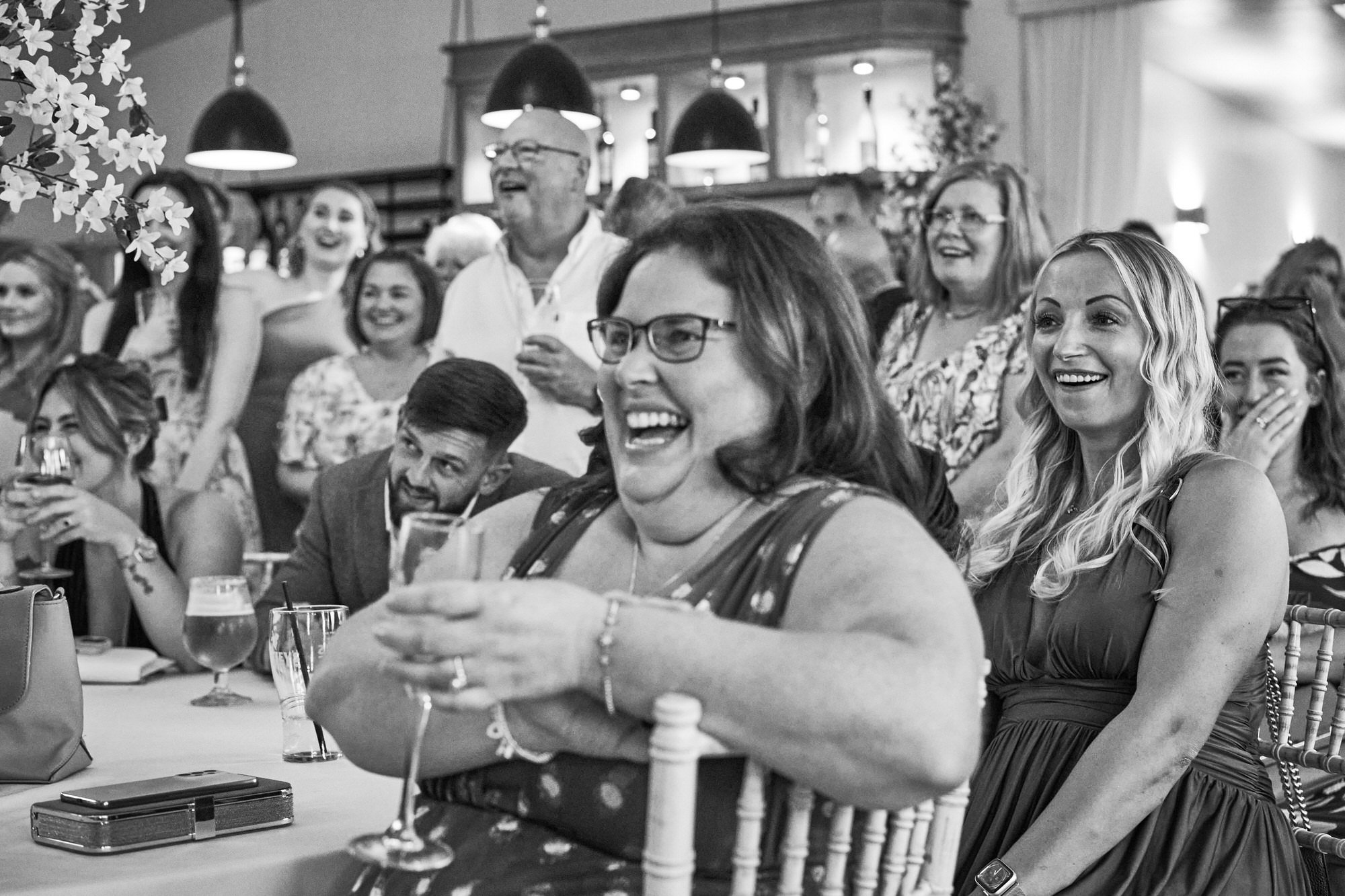 a candid photo of wedding guests laughing during speeches