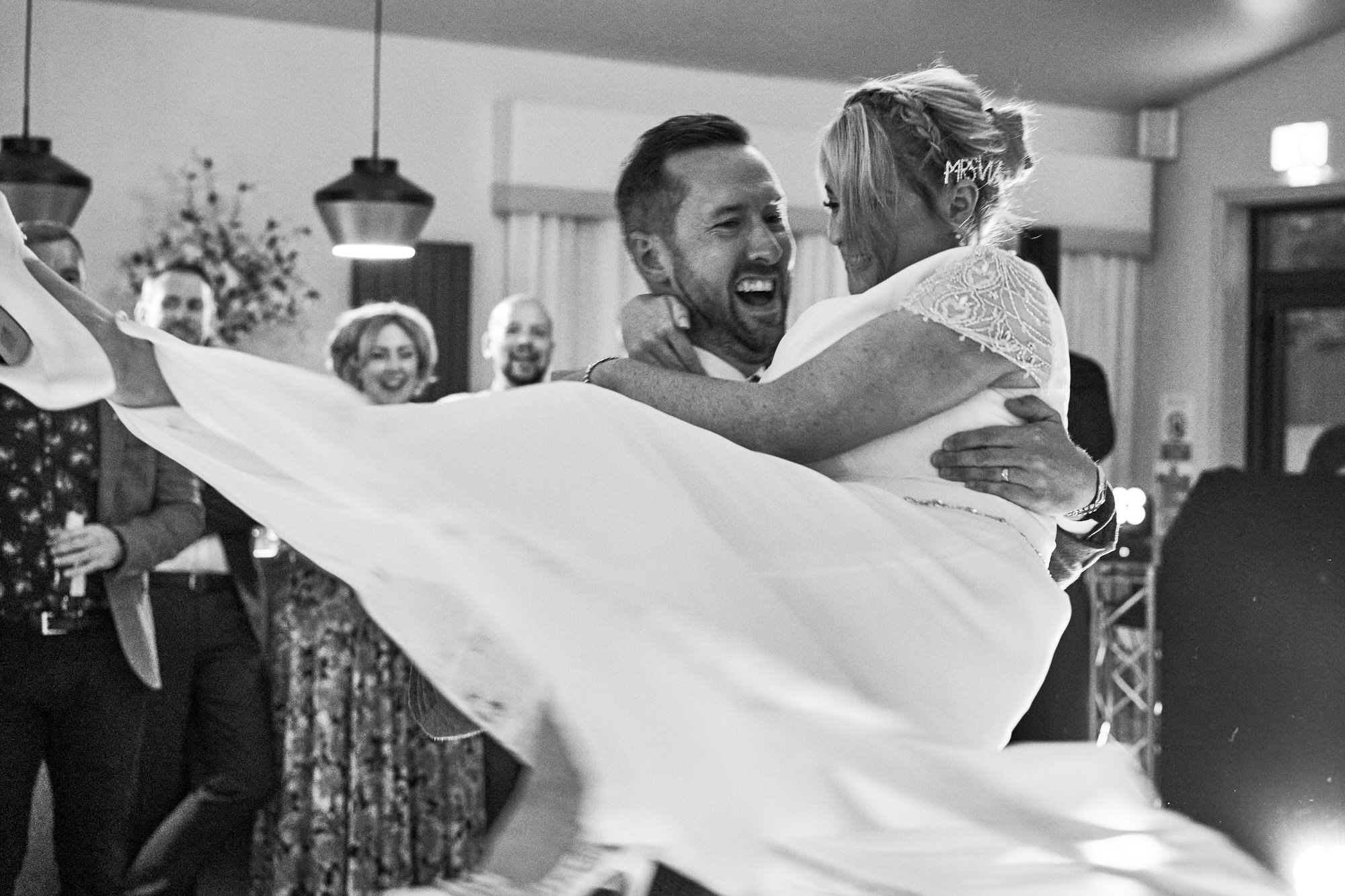 the groom lifts the bride up to spin during their first dance