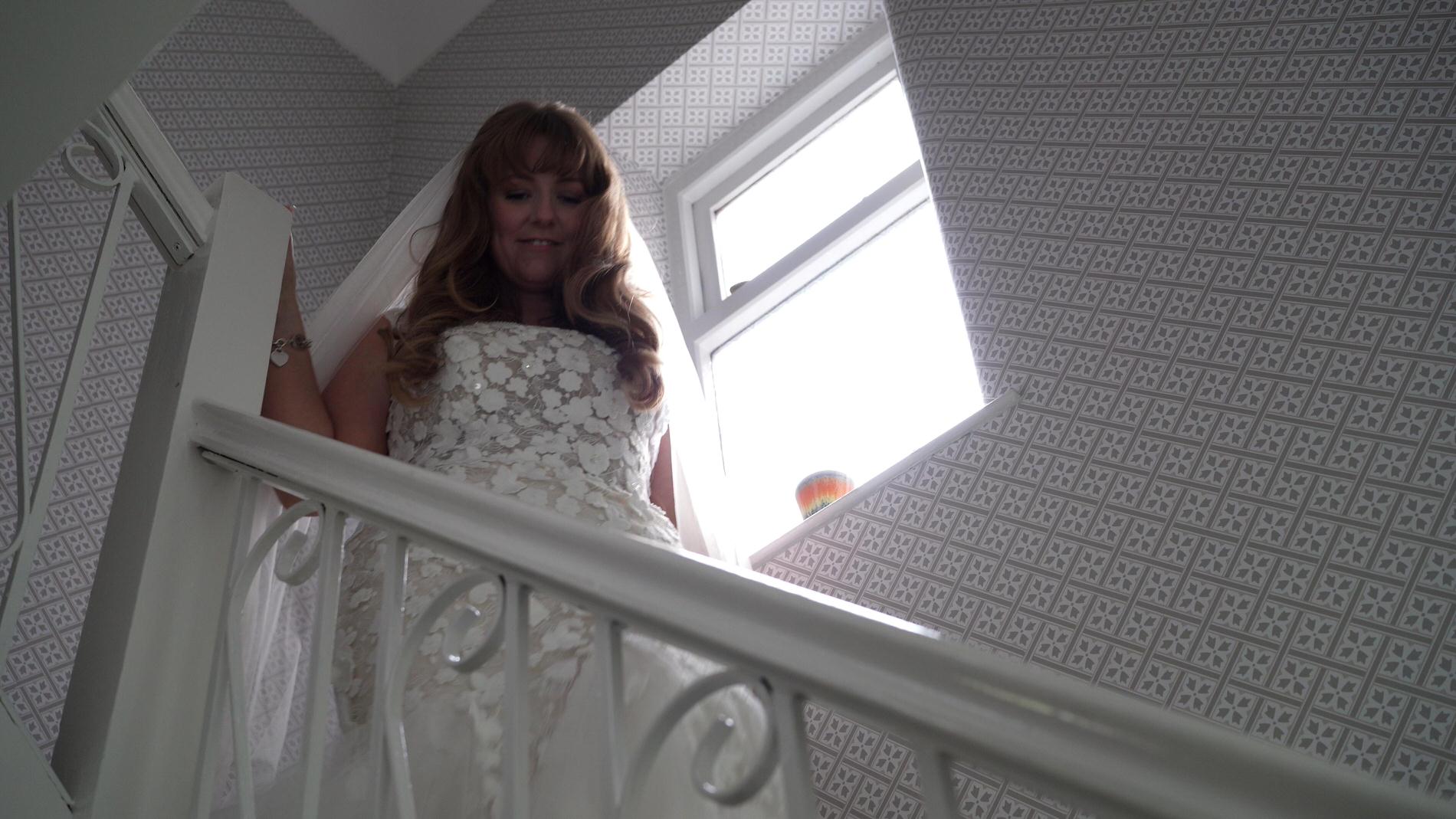 our bride walks down the stairs to reveal to her wedding party