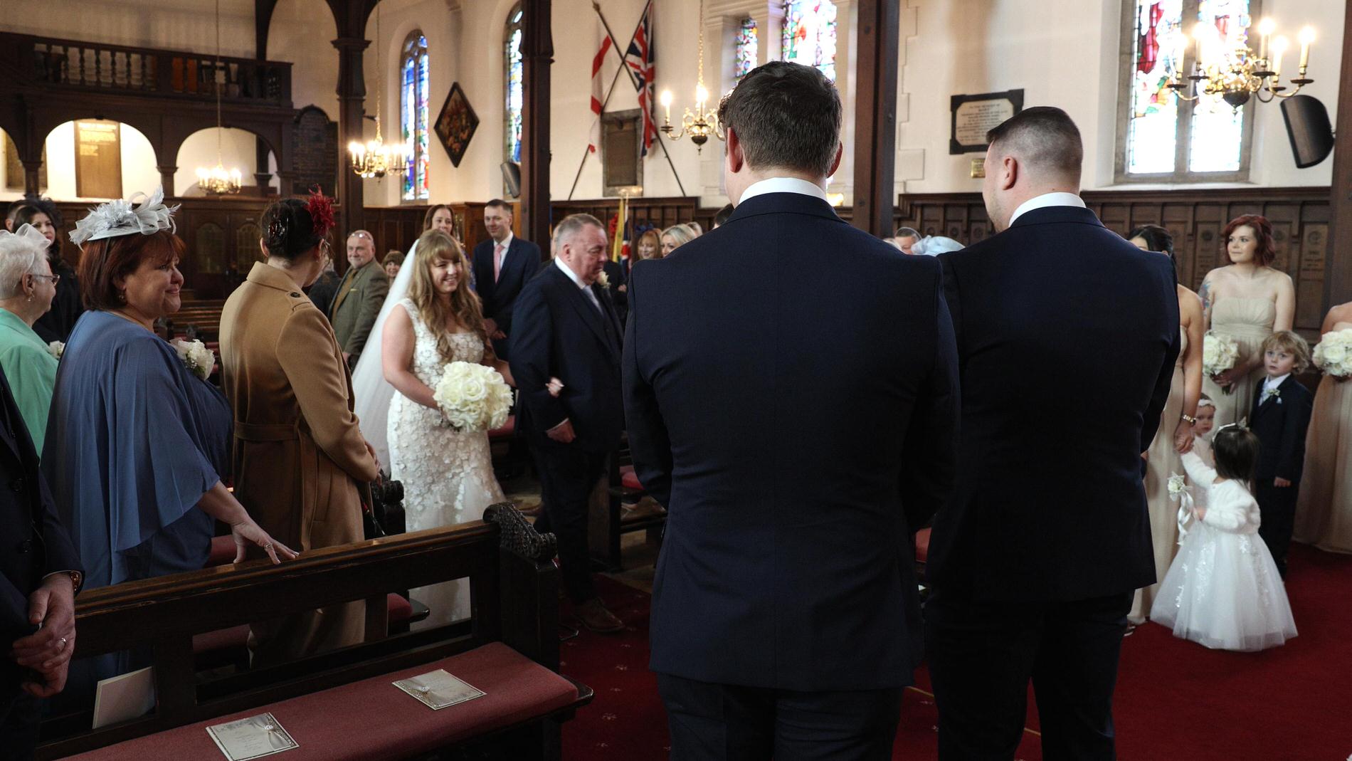 a bride smiles at her groom walking down the aisle in Churchtown