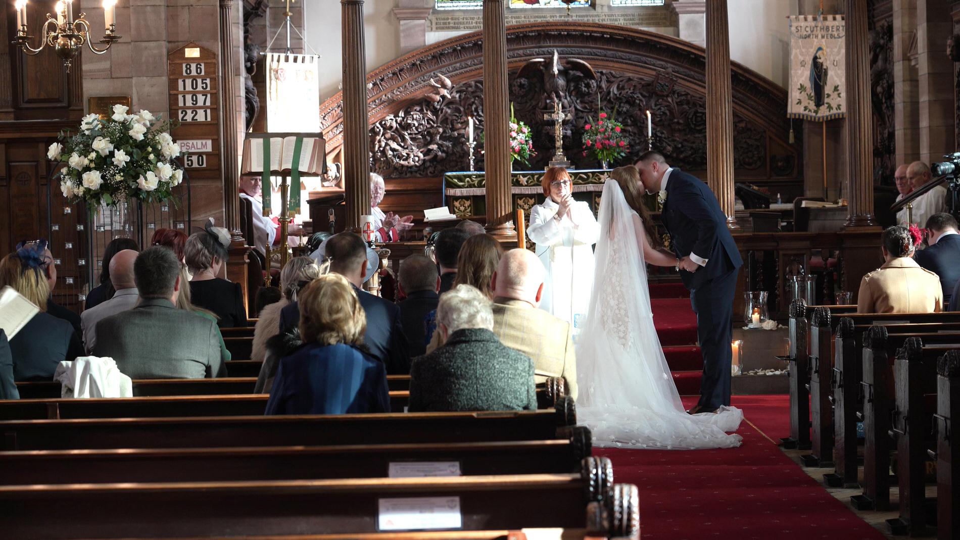 a video still of the couple kissing during ceremony at St Cuthberts Church in Churchtown
