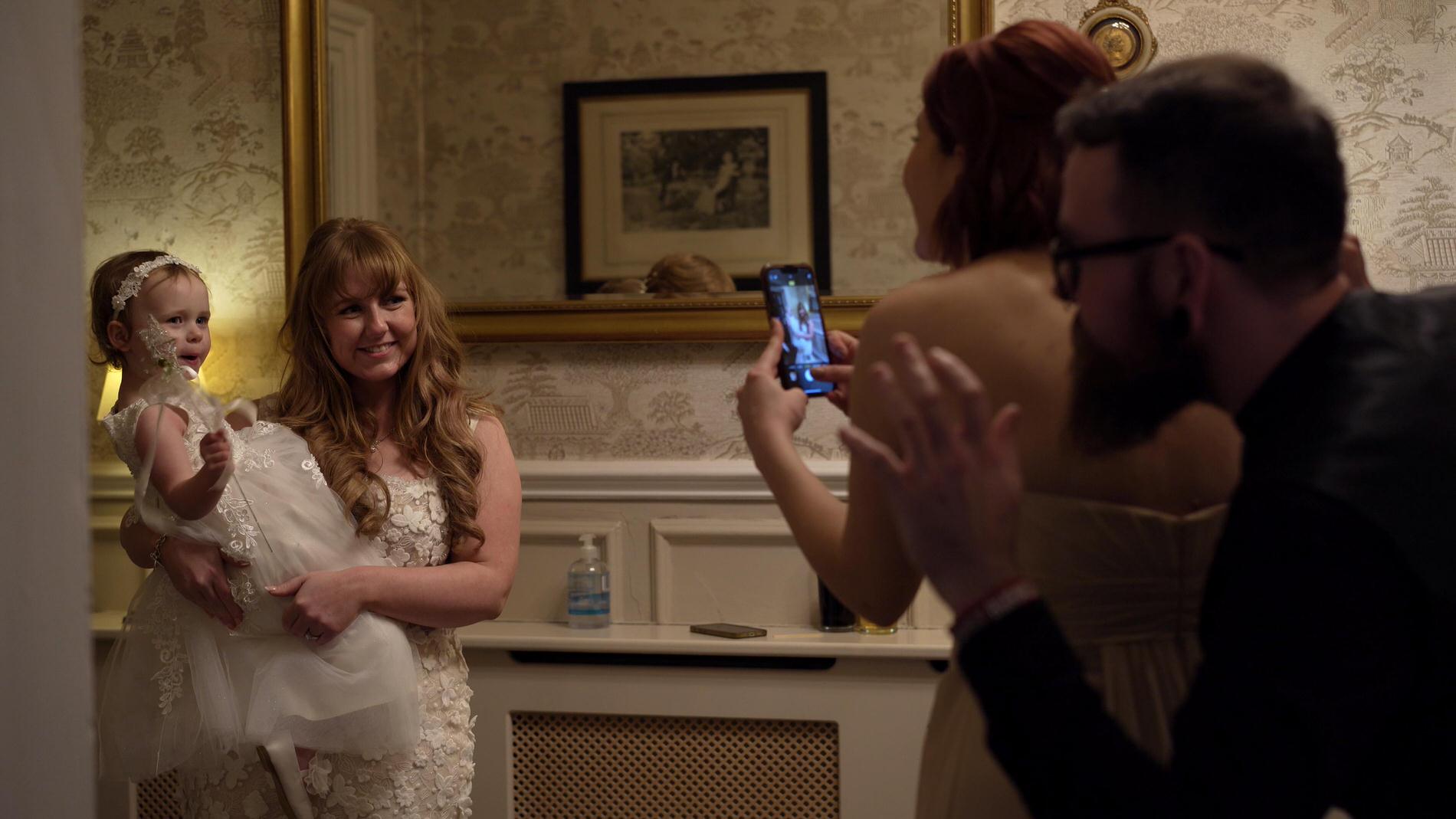 parents make silly faces to make a flowergirl smile for the camera