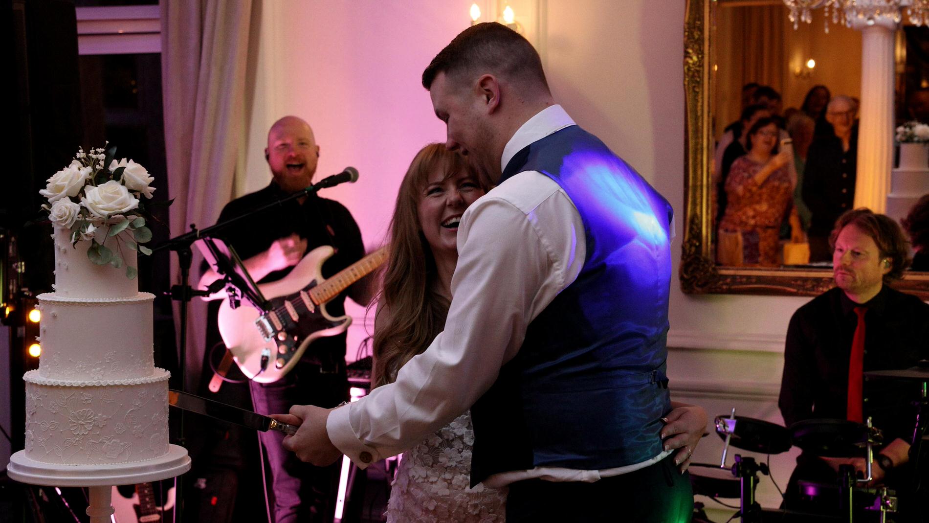 a couple laugh as they cut their wedding cake at Ashfield House Standish