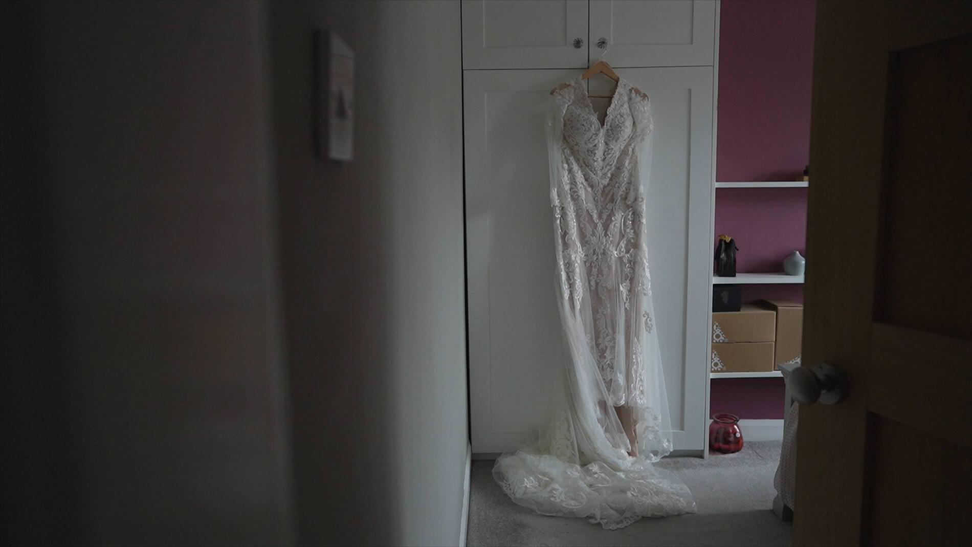 a wedding dress hangs in a bedroom on the morning