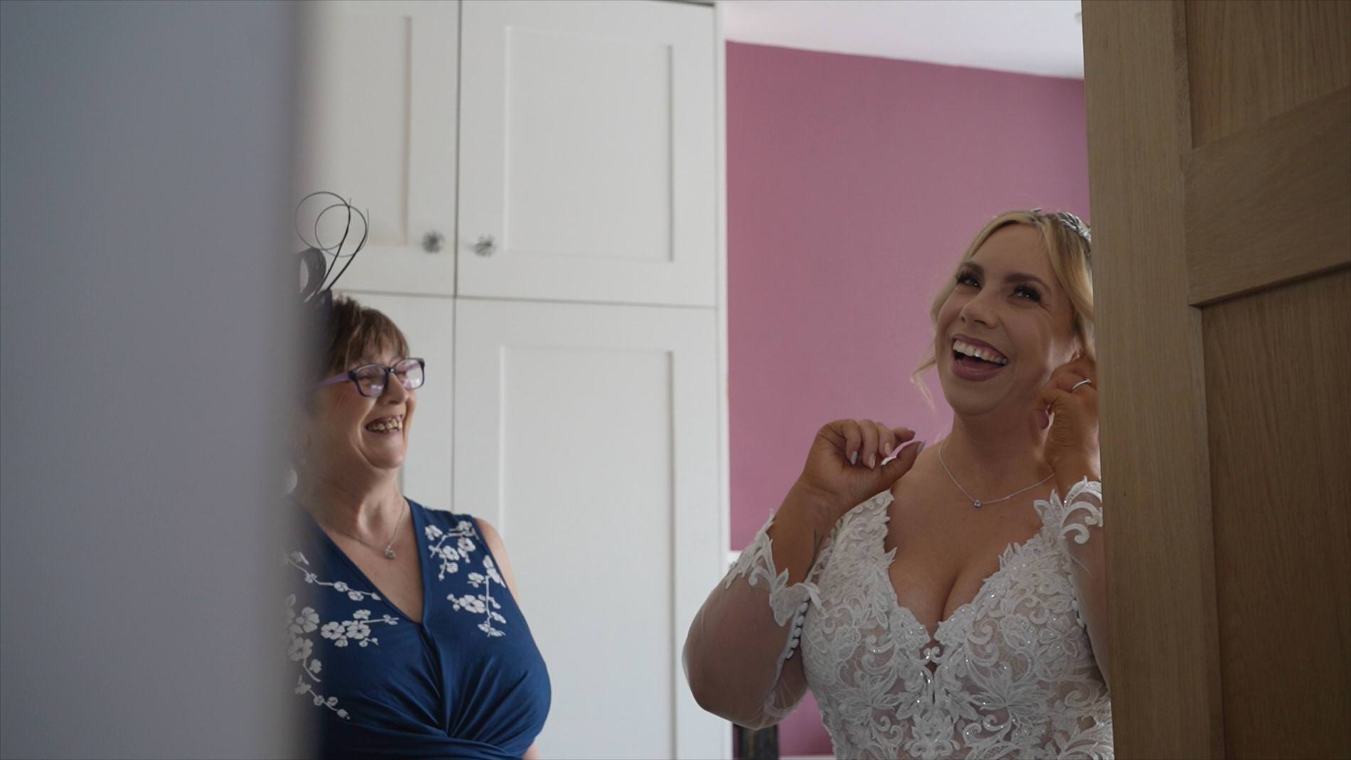 a bride laughs as she puts her wedding earrings in