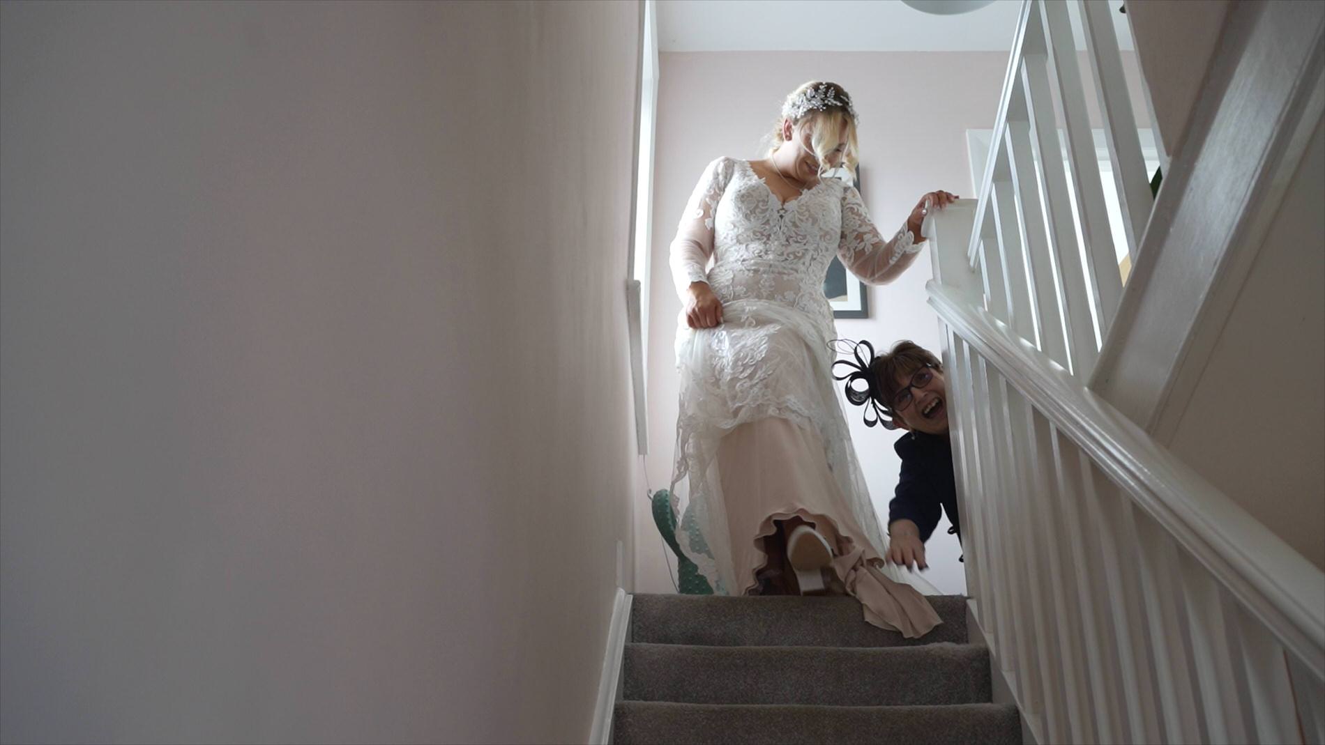 videographer captures a fun candid moment of mum helping the bride down the stairs