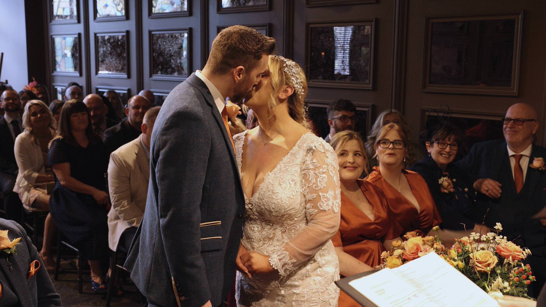 the couple kiss during their wedding ceremony at Manor House Lindley