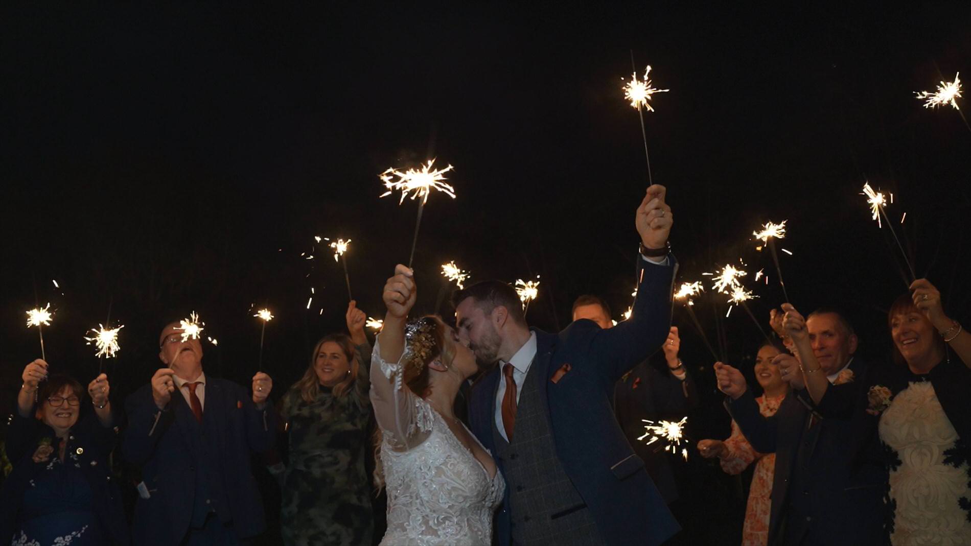 a couple wave sparklers with guests outside Manor House Lindley during a winter wedding