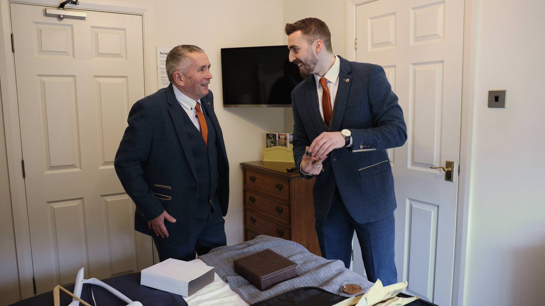 a groom gets ready with his dad in to blue tweed suits