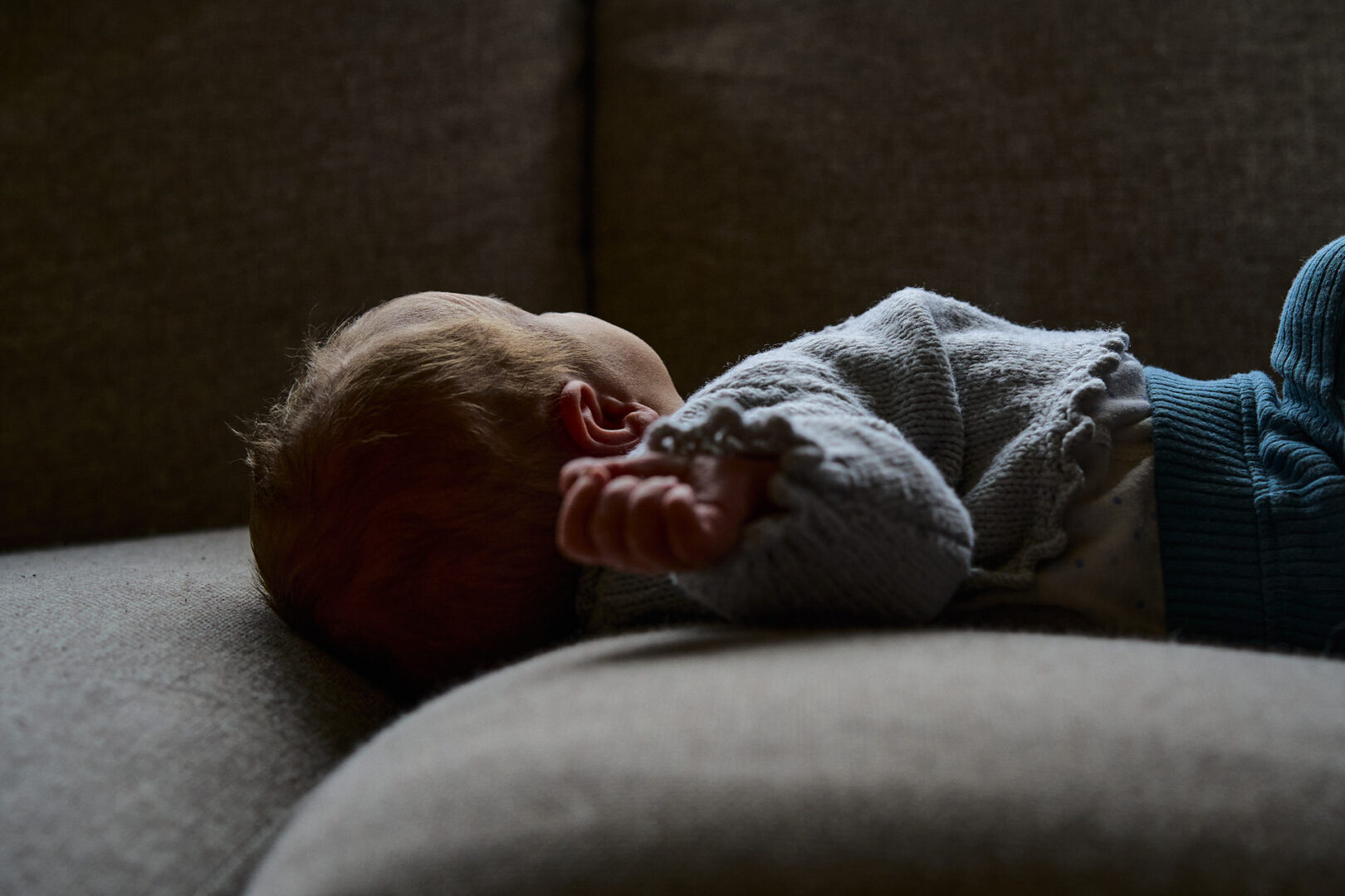 a natural light photo of a newborn baby laying on a sofa