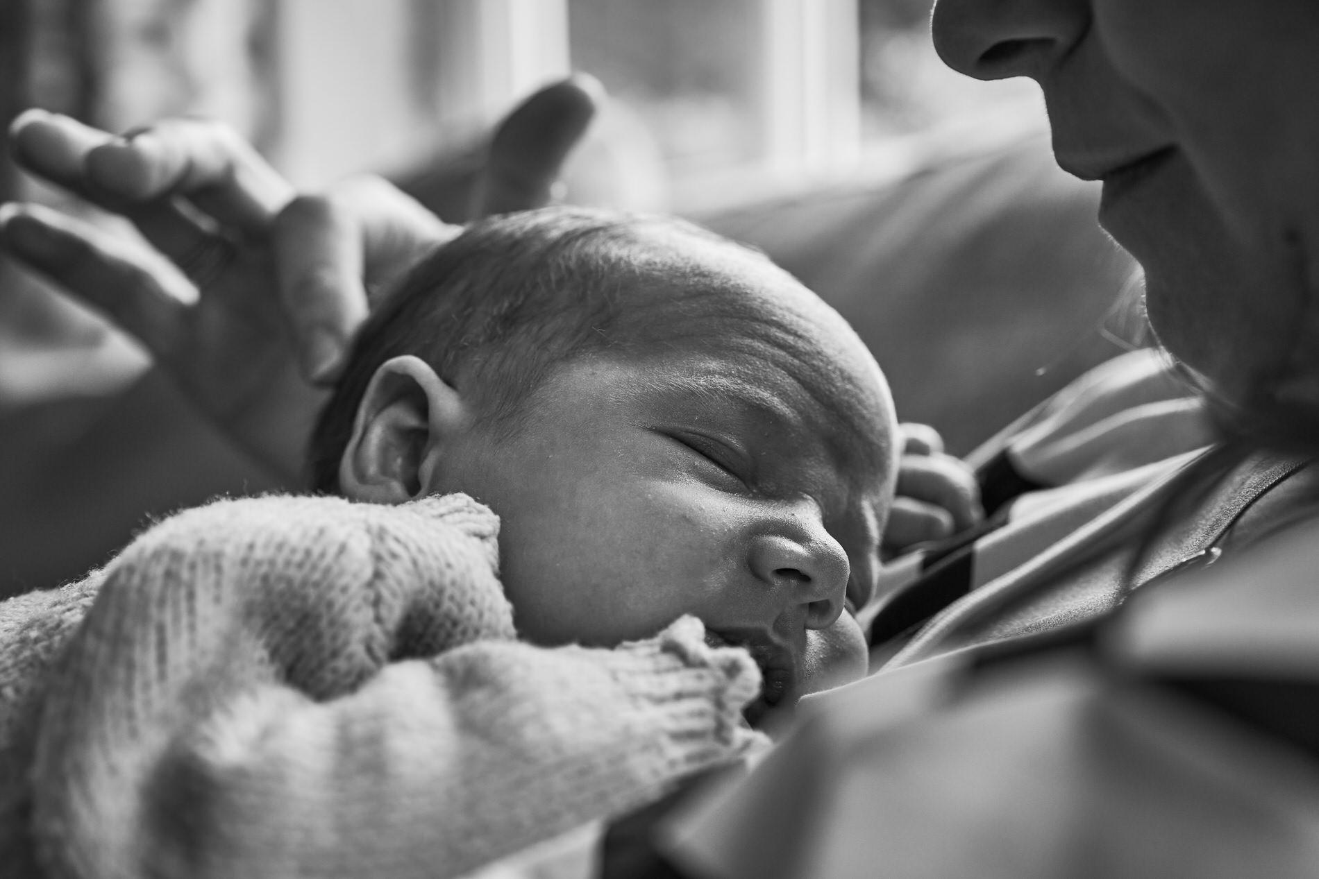 mum gently strokes her babys head as he sleeps on her chest