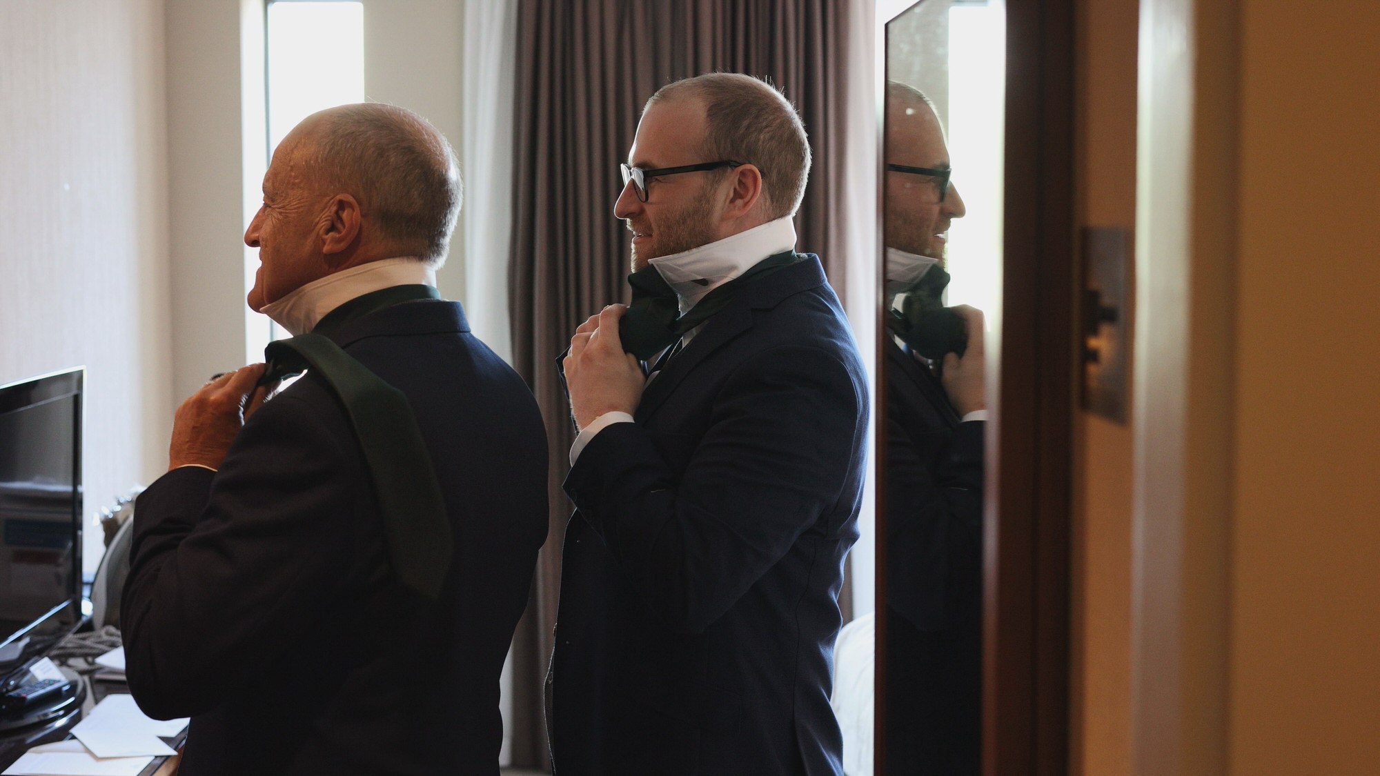 Kirsty and Josh Sefton Palm House Wedding Video 2 a groom adjusts his tie in the mirror with his Dad