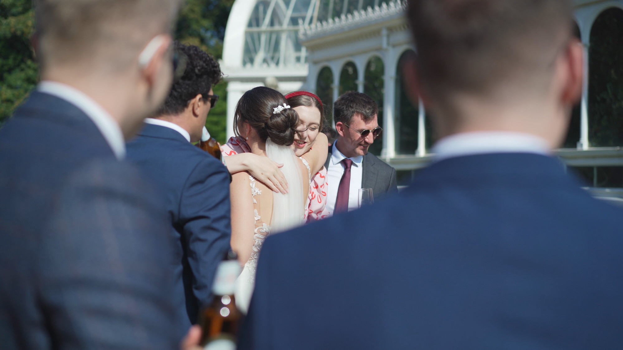 Kirsty and Josh Sefton Palm House Wedding Video 20 a candid video still of guests hugging bride during Sefton Park Palm House wedding