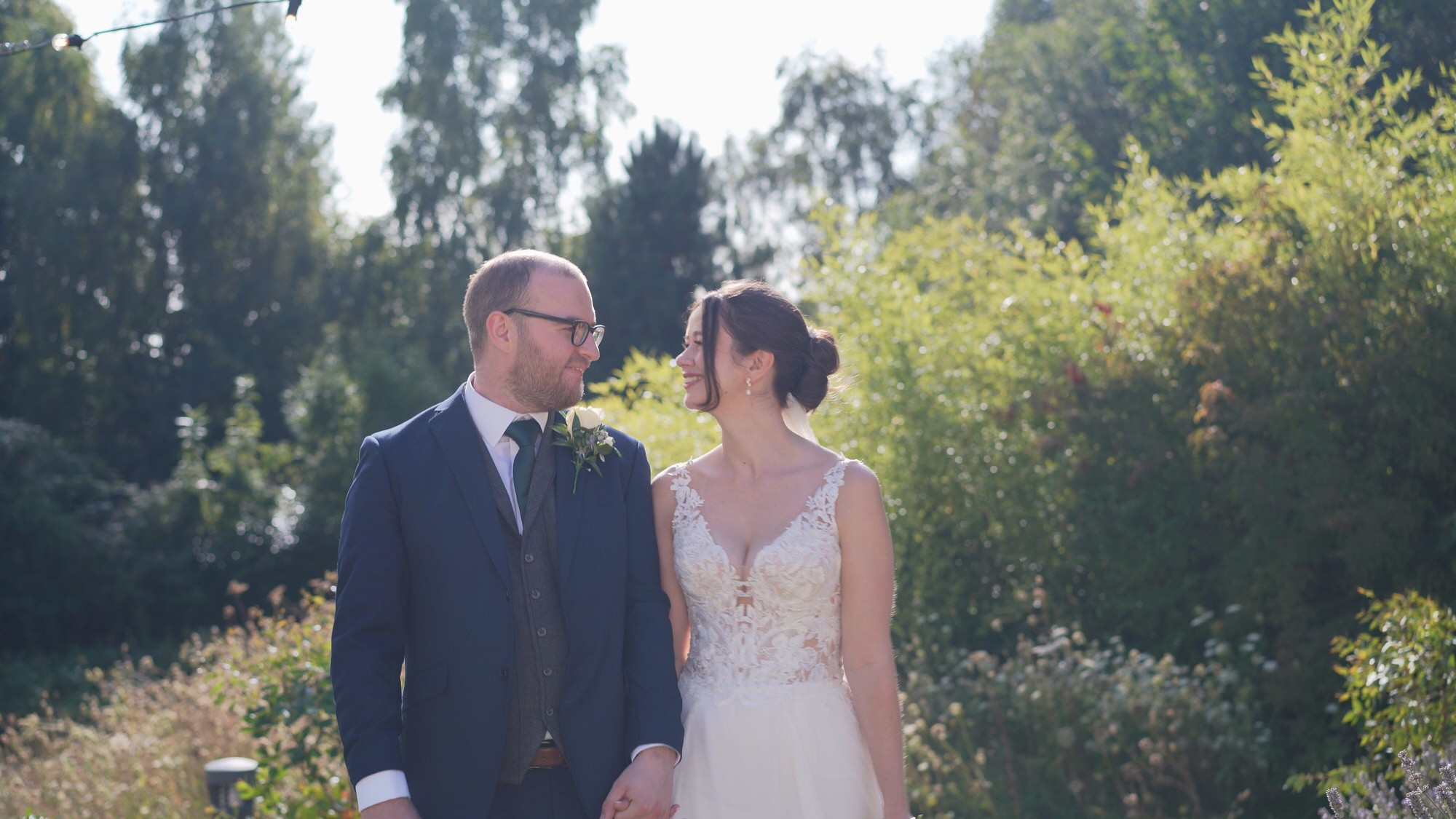 Kirsty and Josh Sefton Palm House Wedding Video 25 a bride and groom smile at each other during natural couples photos outside Sefton Palm House