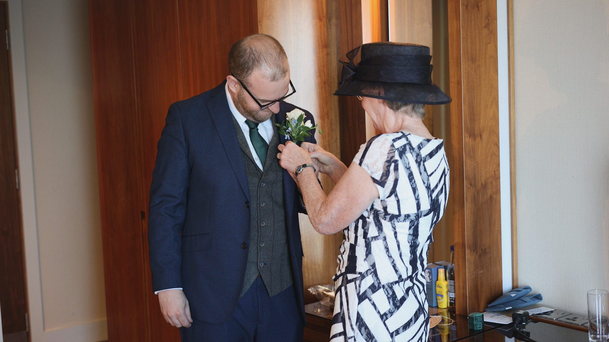Kirsty and Josh Sefton Palm House Wedding Video 3 grooms mum helps adjust a button hole on a wedding morning