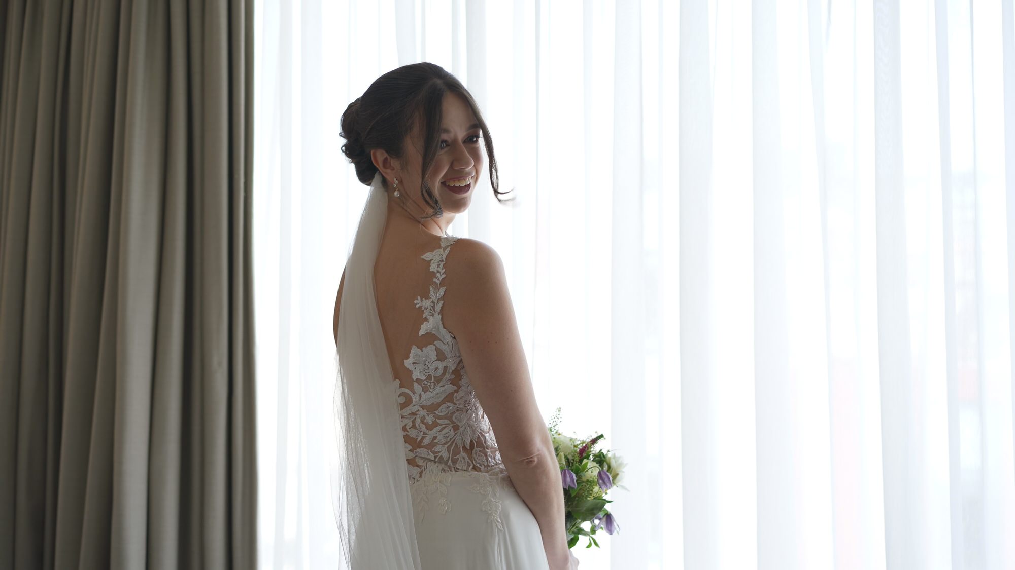 Kirsty and Josh Sefton Palm House Wedding Video 5 a candid video still of a bride smiling at her bridesmaids in her dress